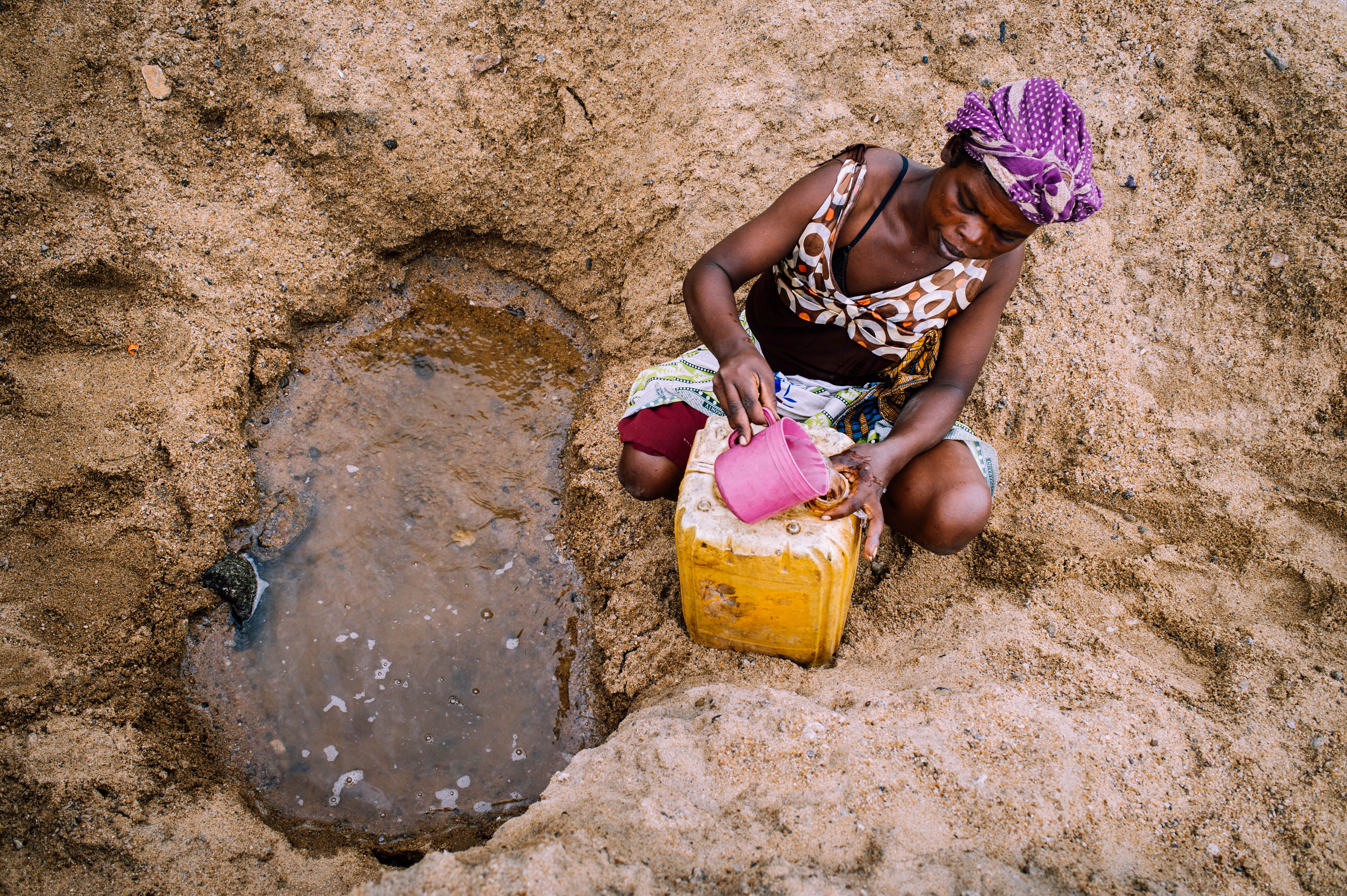 A woman collects water from a puddle in the dried Manambovo river bed in Tsihombe