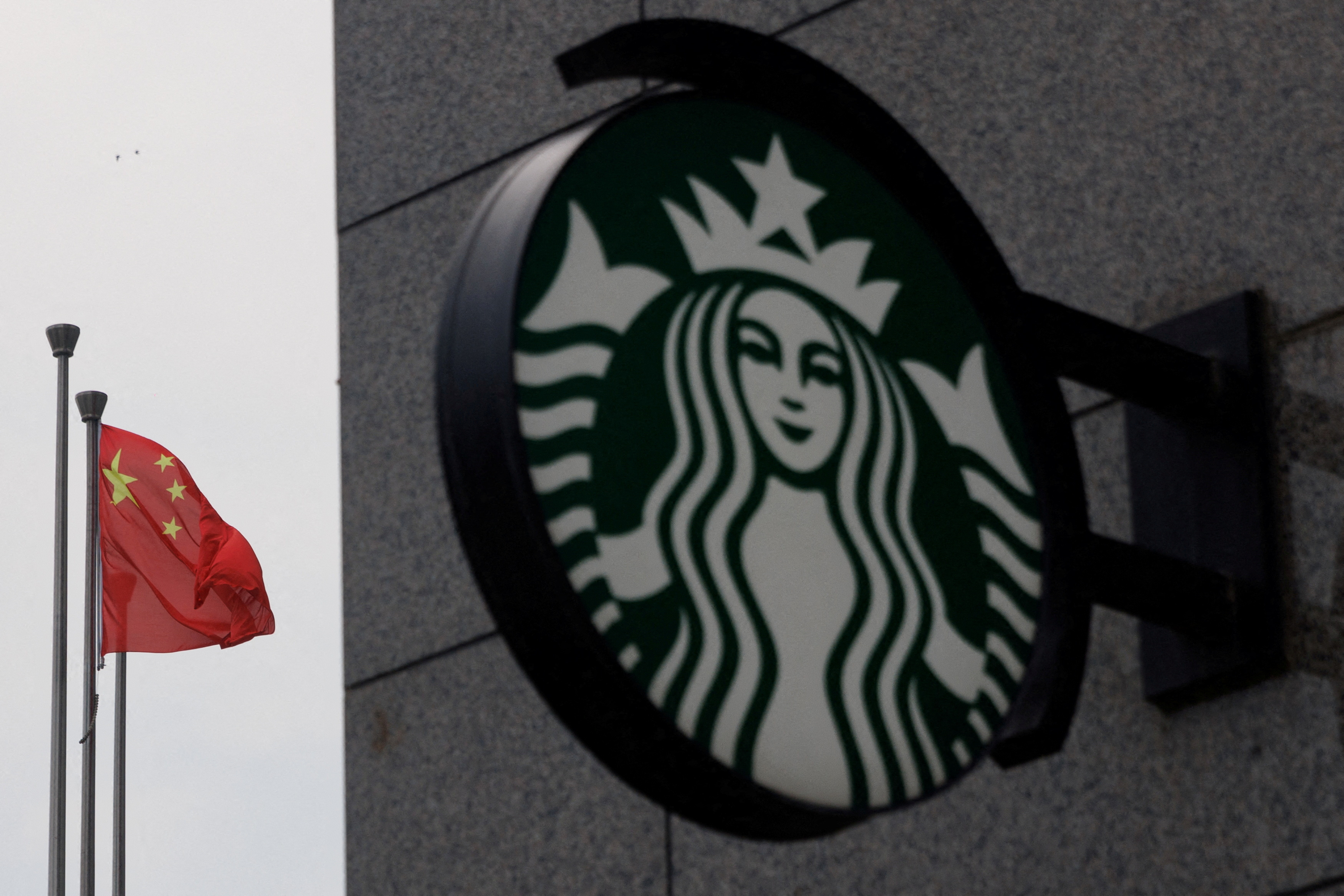 The Chinese flag flies near the Starbucks logo outside a cafe of the coffee chain in Beijing
