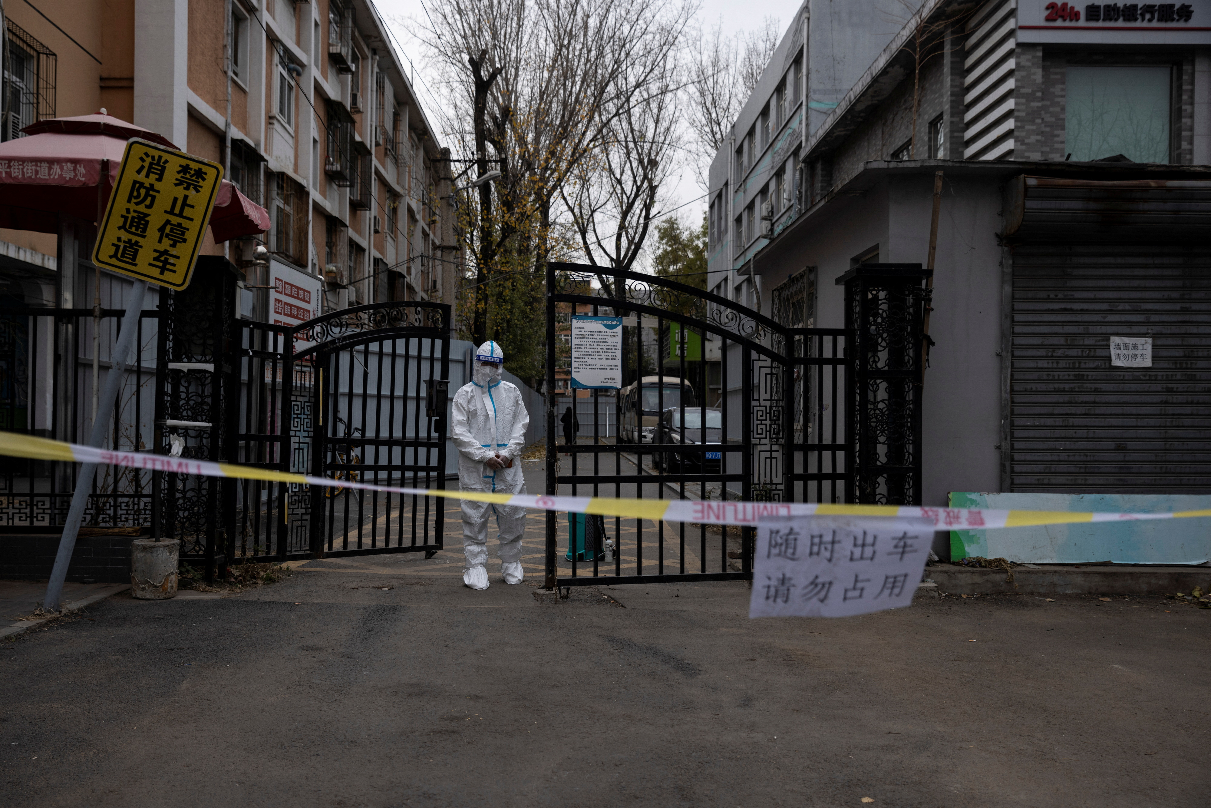 An epidemic-prevention worker in a protective suit stands guard at the gate of a residential compound as coronavirus disease (COVID-19) outbreaks continue in Beijing
