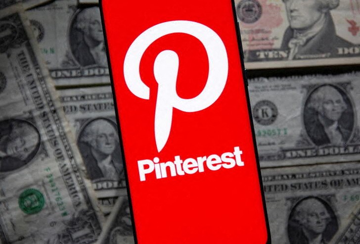 Pinterest logo is seen on a smartphone placed over U.S. dollar banknotes in this illustration