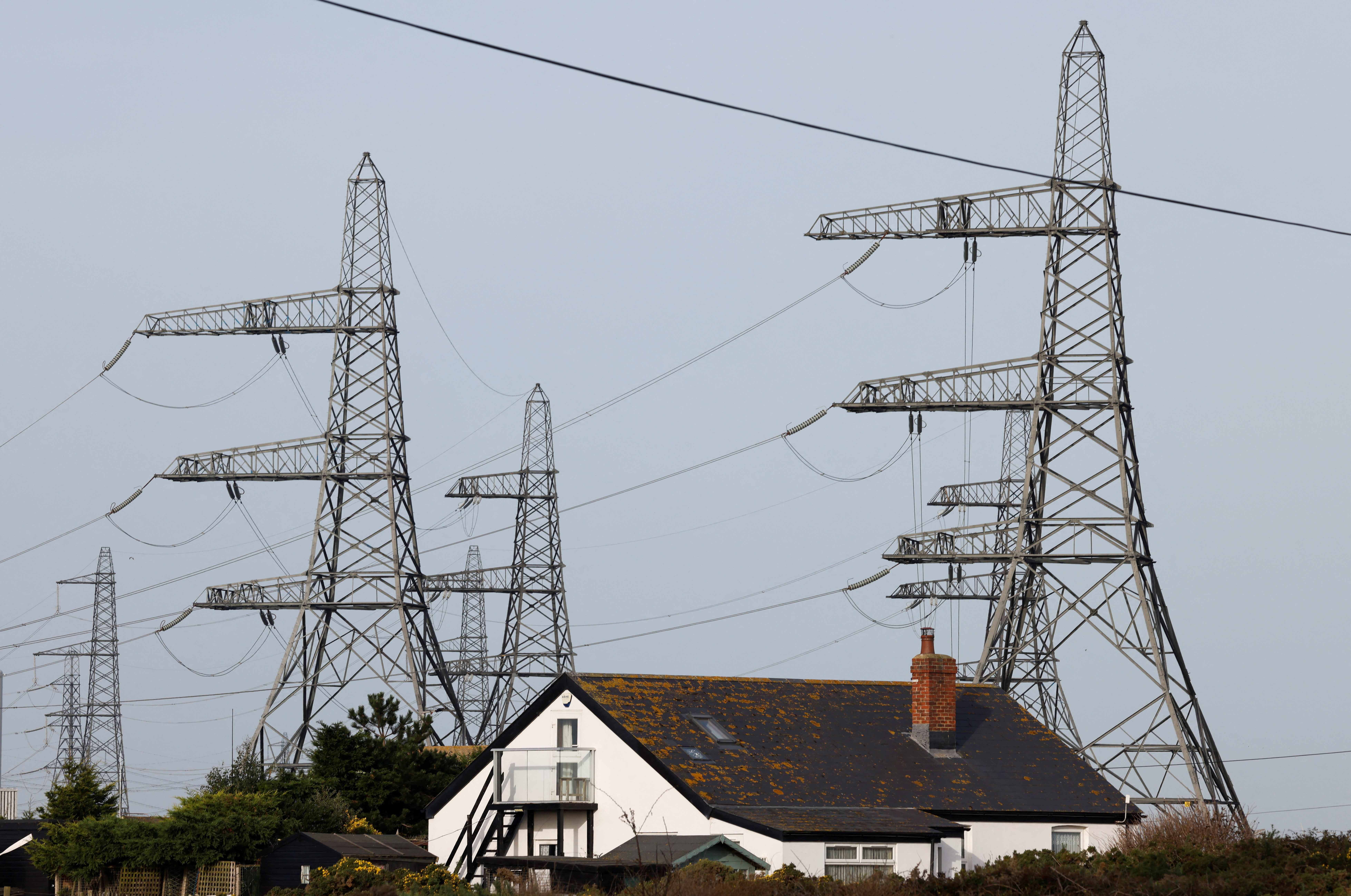 Electricity pylons connected to the Dungeness B power station are seen behind a local house in Dungeness