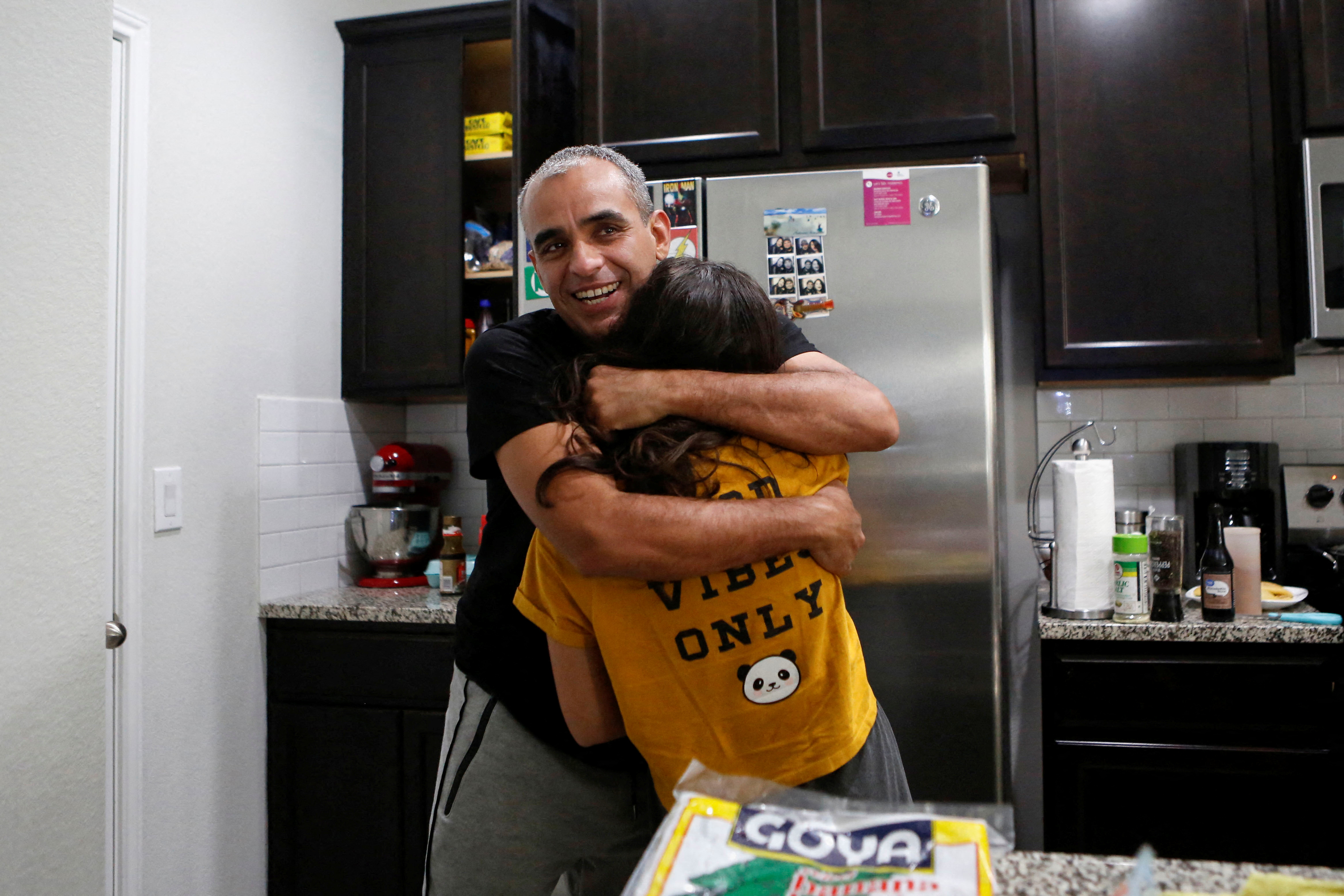Anibal Pirela embraces his 12-year-old daughter Paula in the apartment he lives in with his family after migrating from Maracaibo, Venezuela and enrolling in a Department of Homeland Security program that allows migrants release with an ankle monitor, in Austin, Texas, U.S. December 22, 2021. REUTERS/Marco Bello