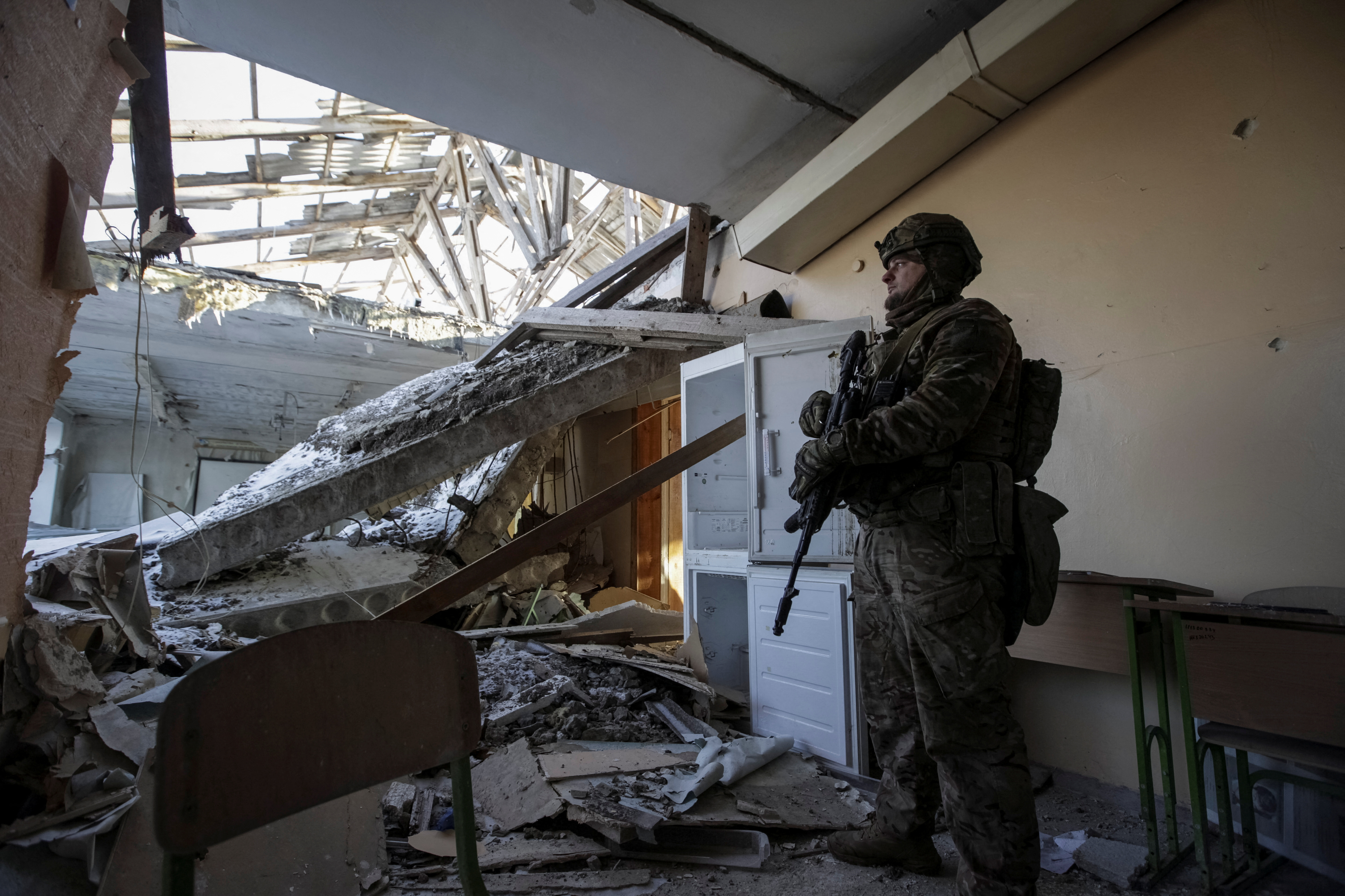 A Ukrainian serviceman is seen in a destroyed building of school at a frontline in Donetsk region