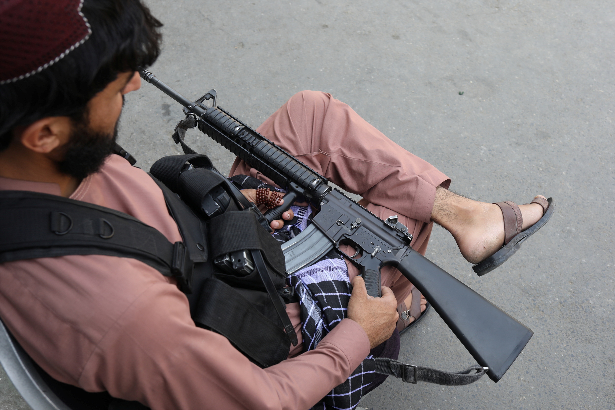 A member of the Taliban sits while holding his gun in Kabul