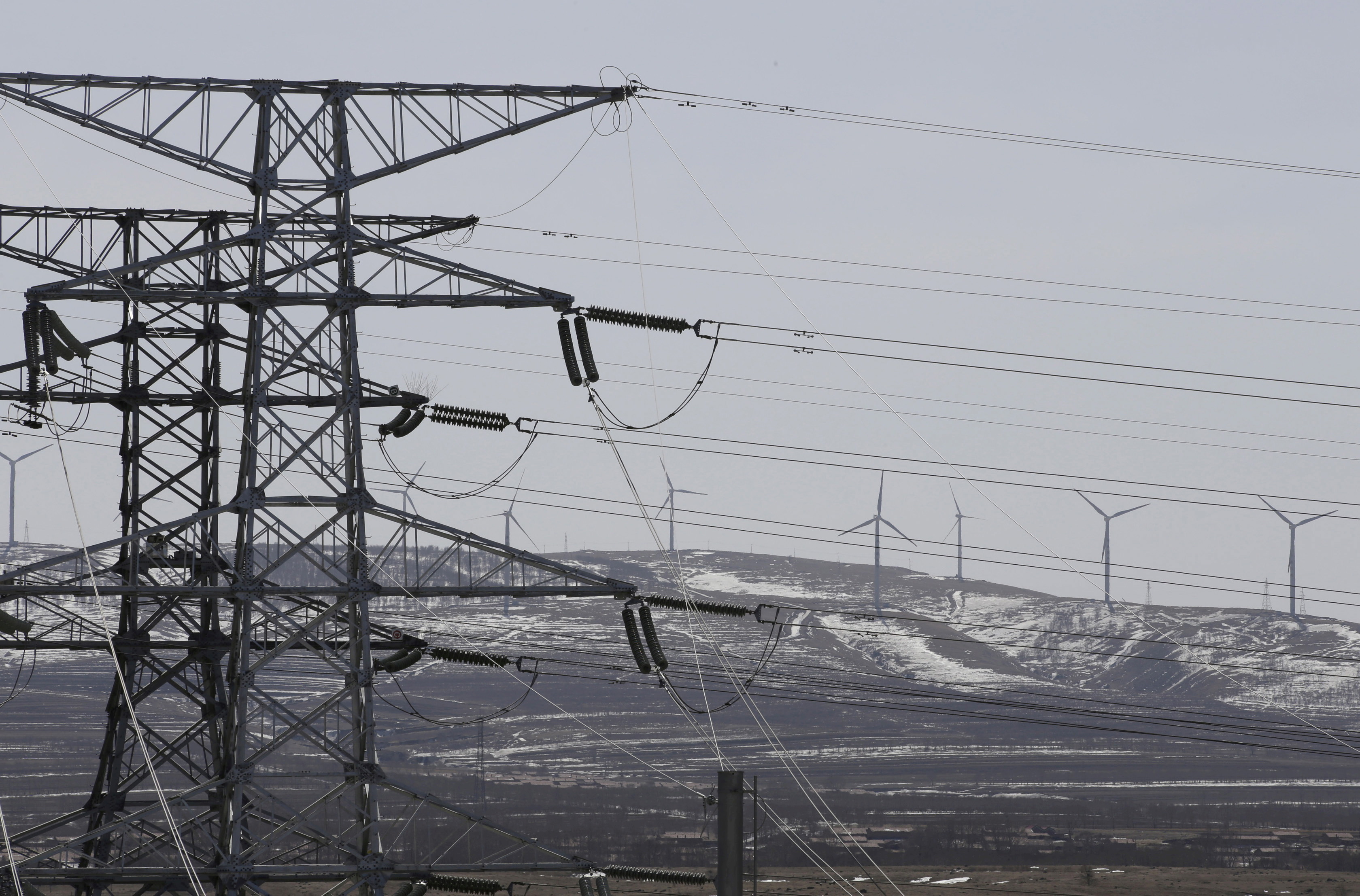 FILE PHOTO: Power lines and wind turbines are pictured at a wind and solar energy storage and transmission power station in Zhangjiakou