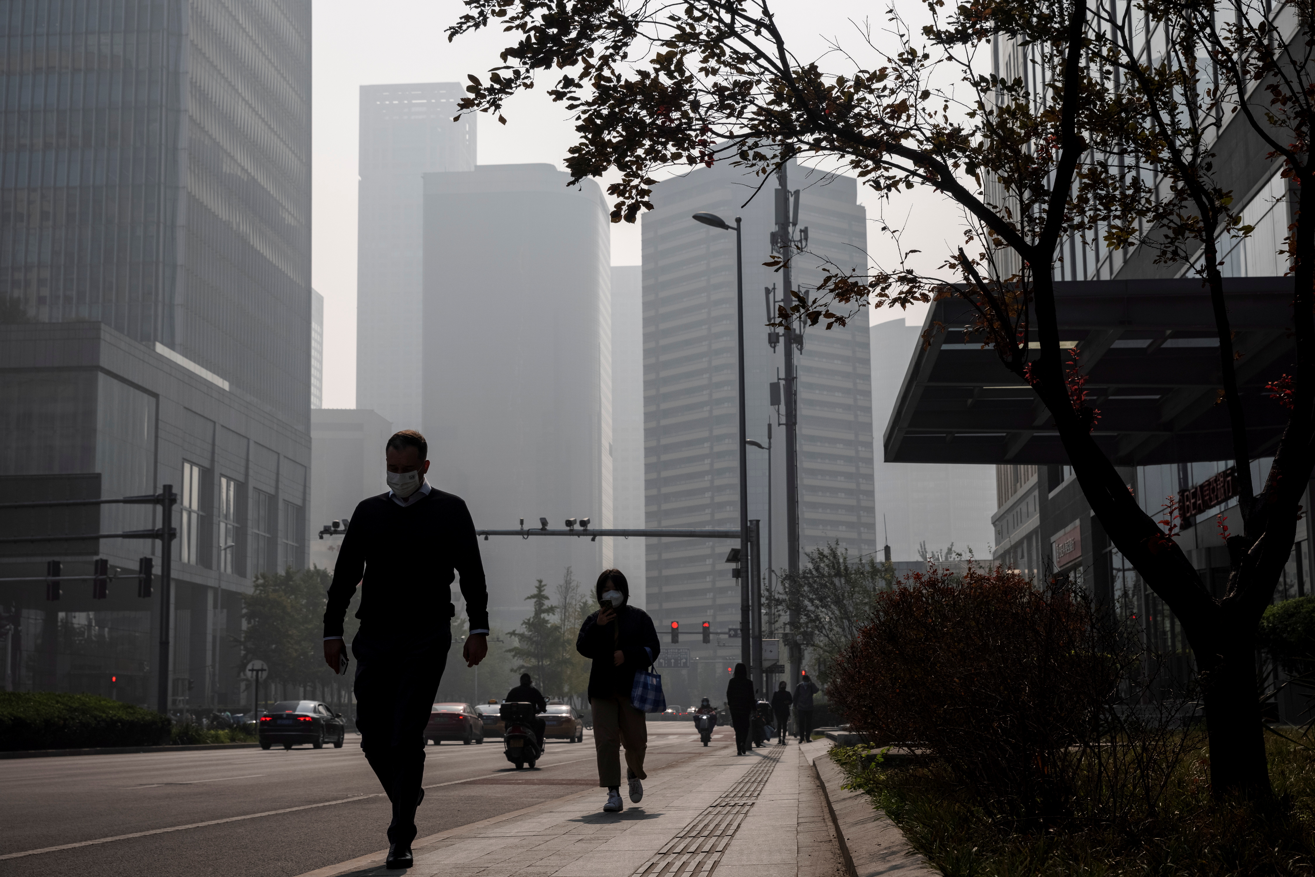 People walk in the Central Business District (CBD) on a hazy morning in Beijing