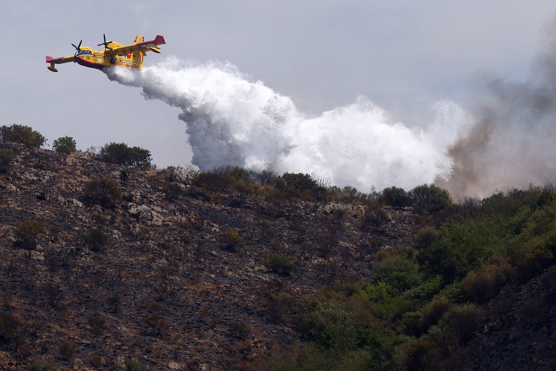 A firefighting airplane drops water as a wildfire burns in the Monte Catillo nature reserve in Tivoli, near Rome, Italy, August 13, 2021. REUTERS/Guglielmo Mangiapane