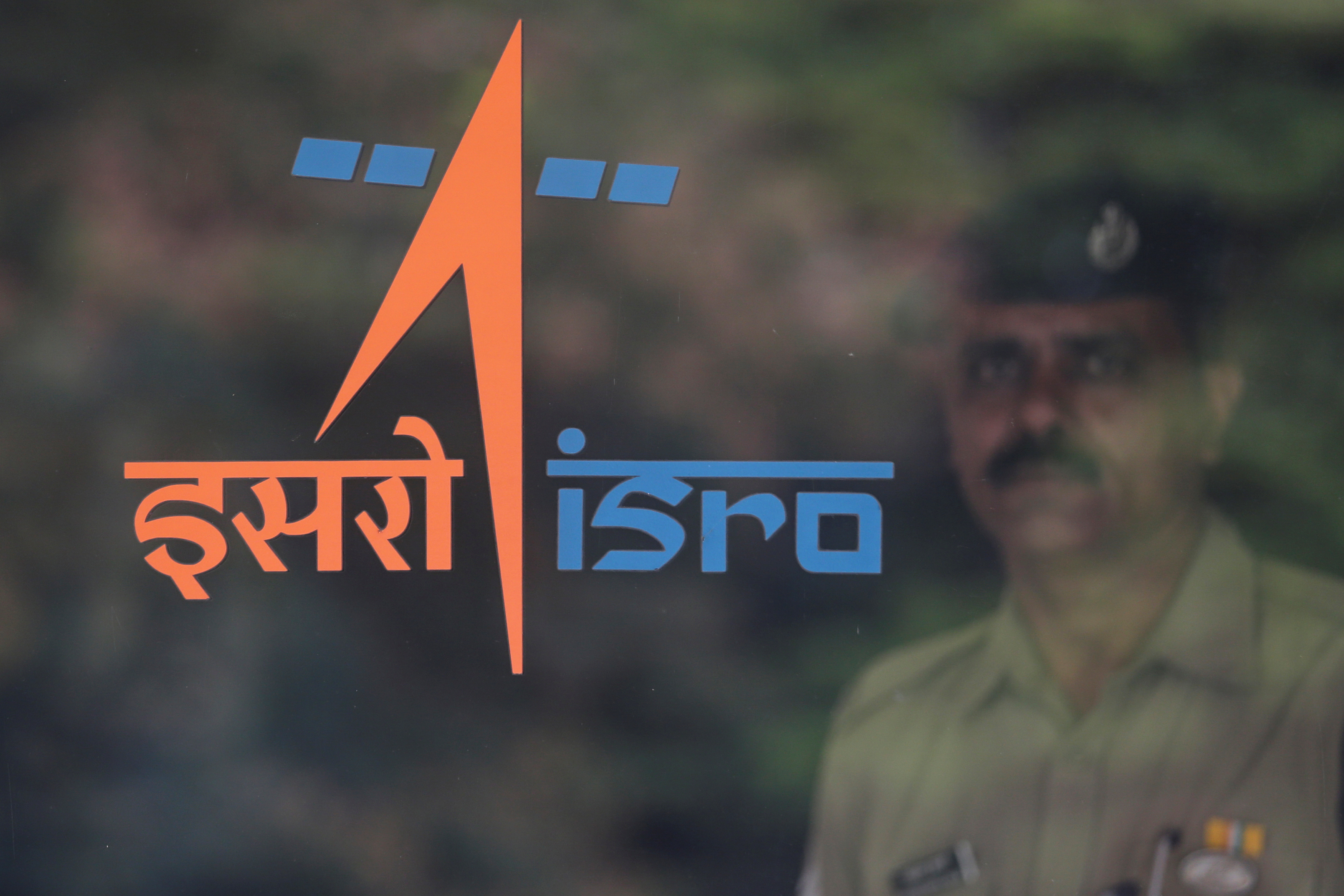 A security guard stands behind the logo of Indian Space Research Organisation (ISRO) at its headquarters in Bengaluru