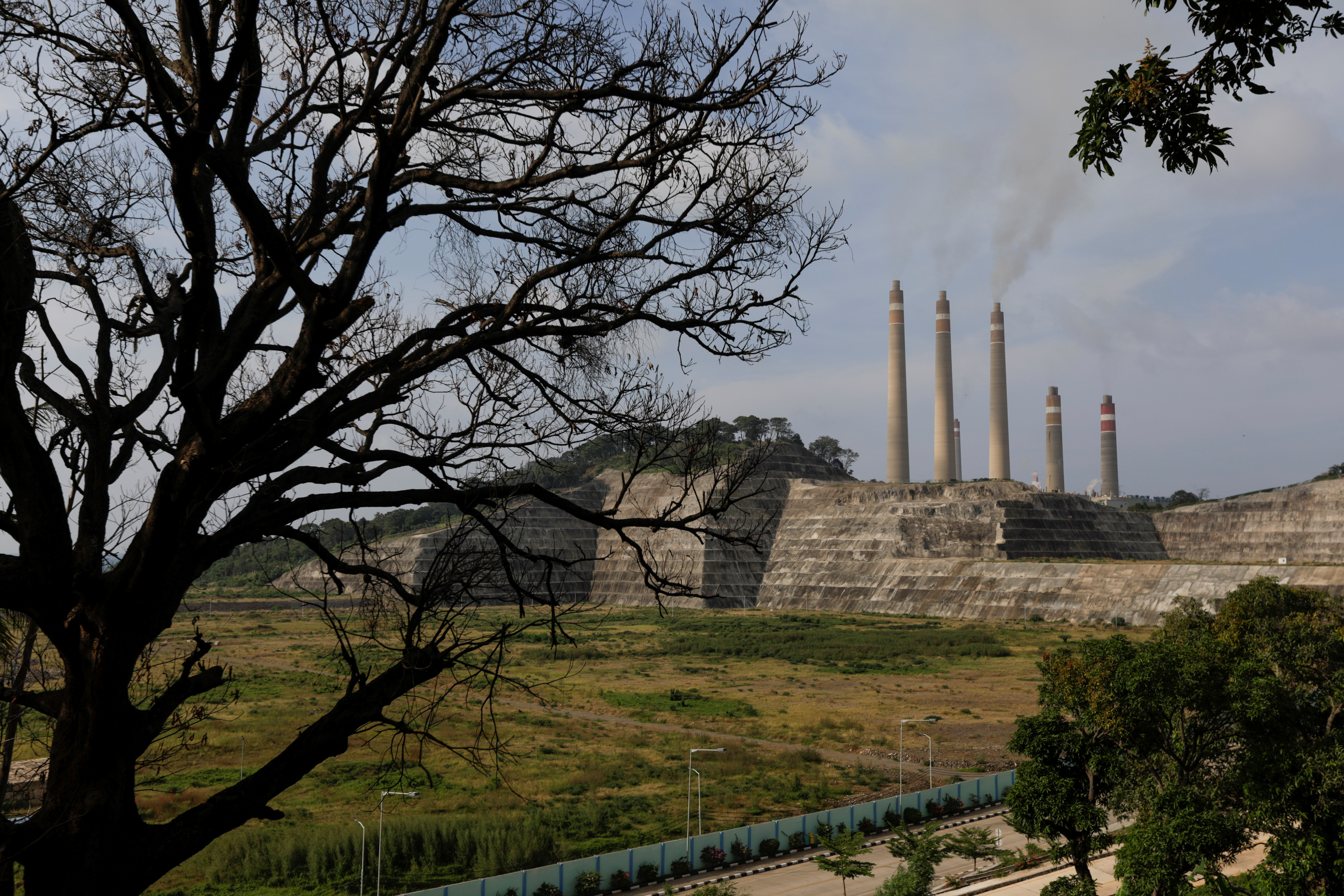 Smoke and steam billows from the coal-fired power plant owned by Indonesia Power, next to an empty area for Java 9 and 10 Coal-Fired Steam Power Plant Project in Suralaya