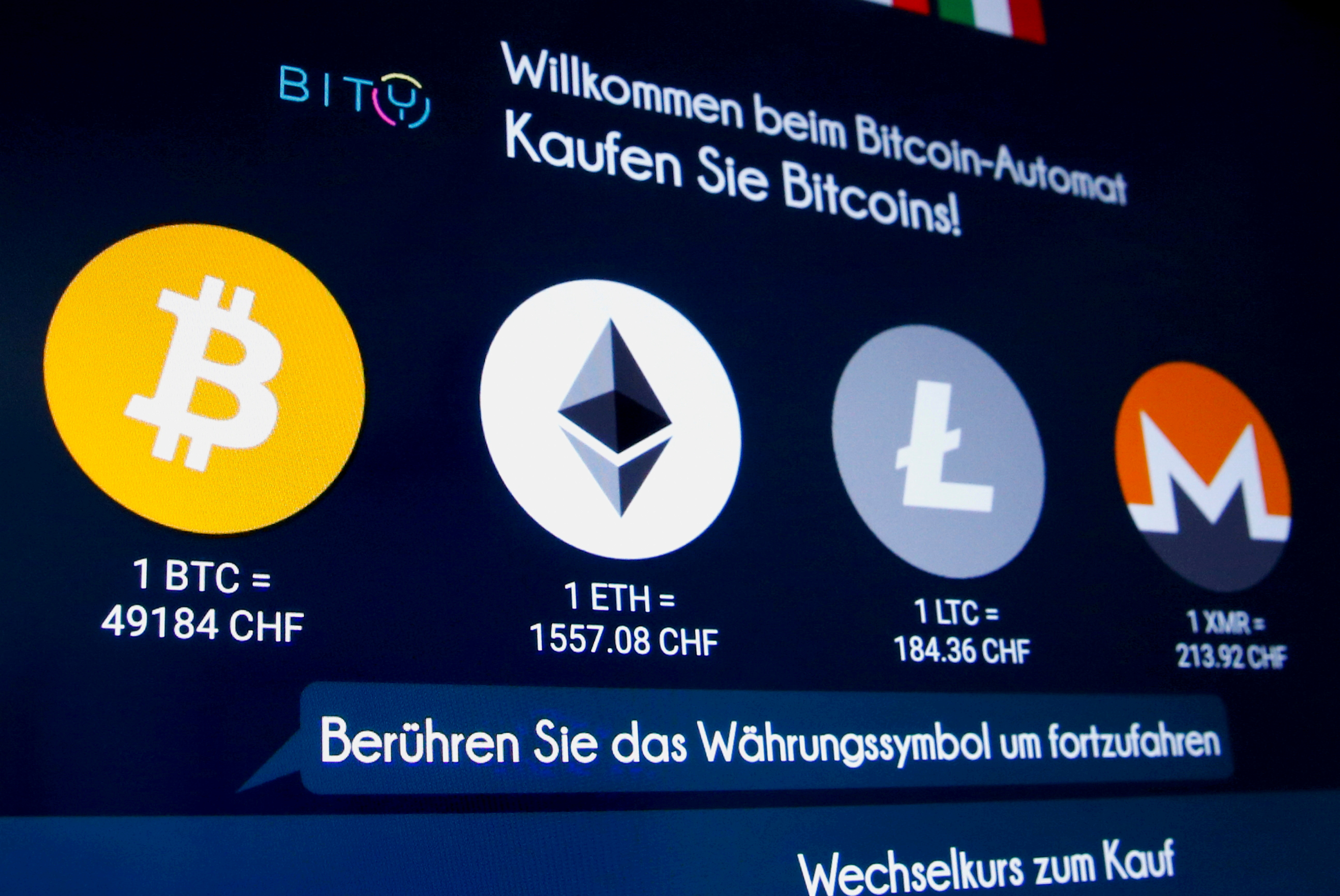 The exchange rates and logos of Bitcoin, Ether, Litecoin and Monero are seen on the display of a cryptocurrency ATM in Zurich