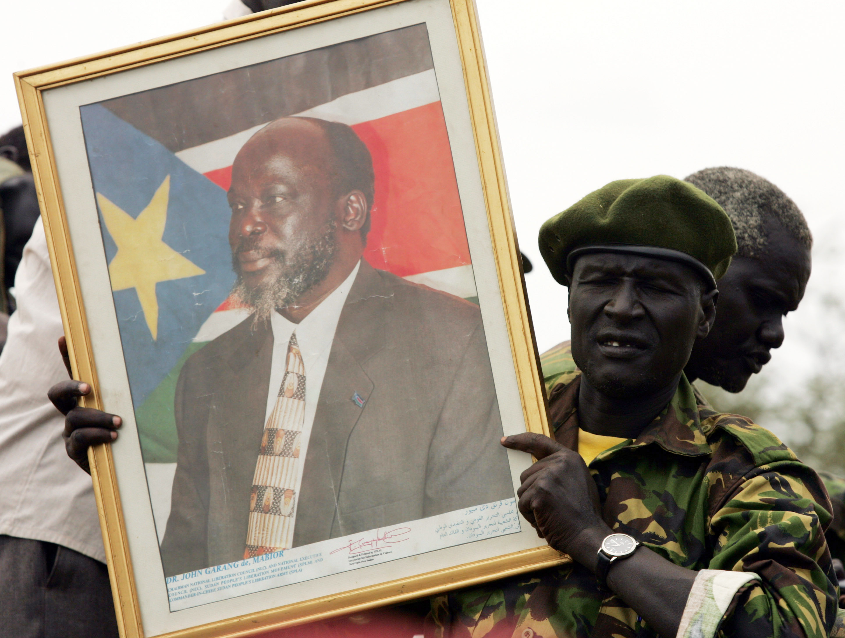 Soldier holds portrait of late former rebel leader Garang, Sudan.
