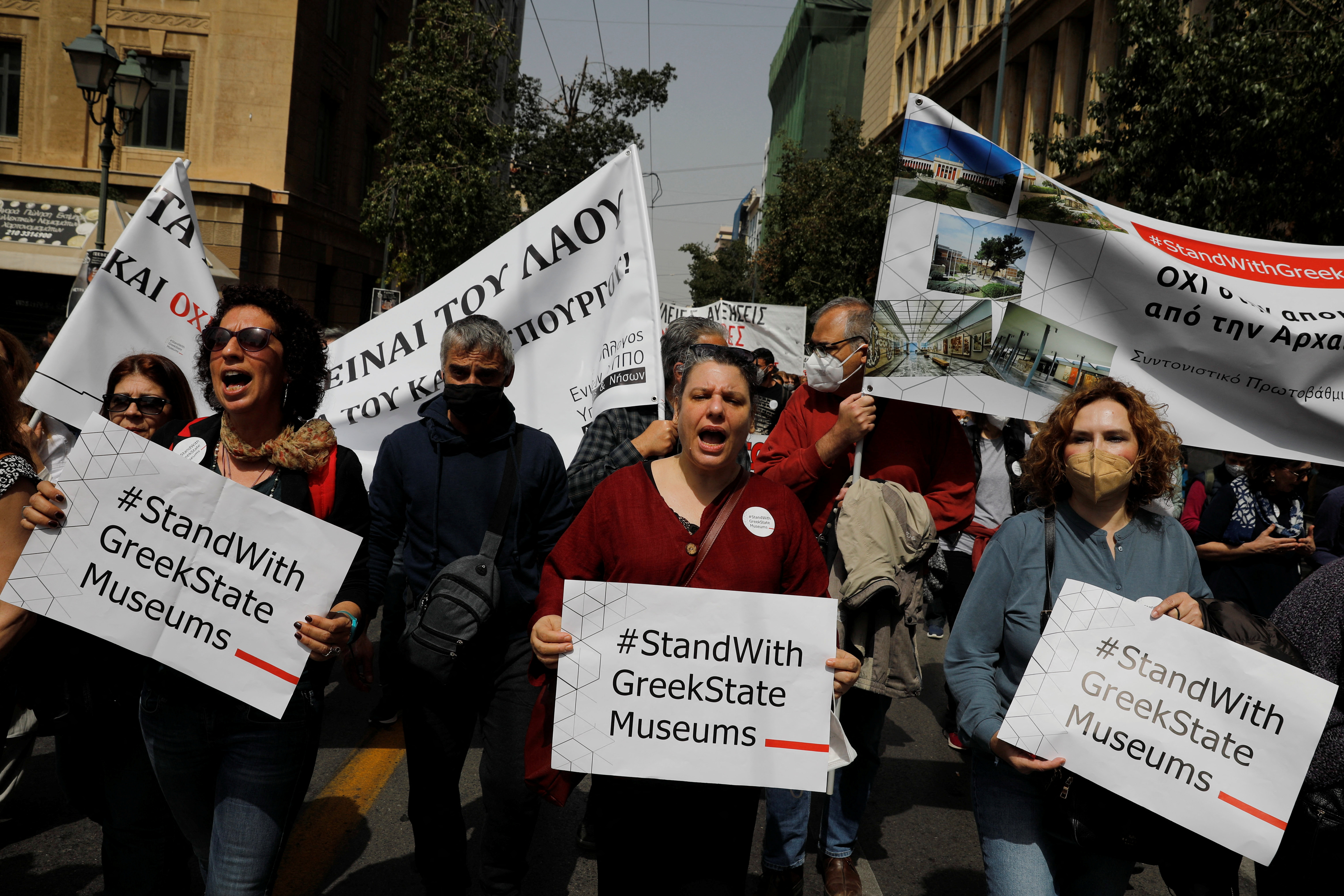 People hold placards as they take part in a protest during a 24-hour strike over high prices and low wages in Athens