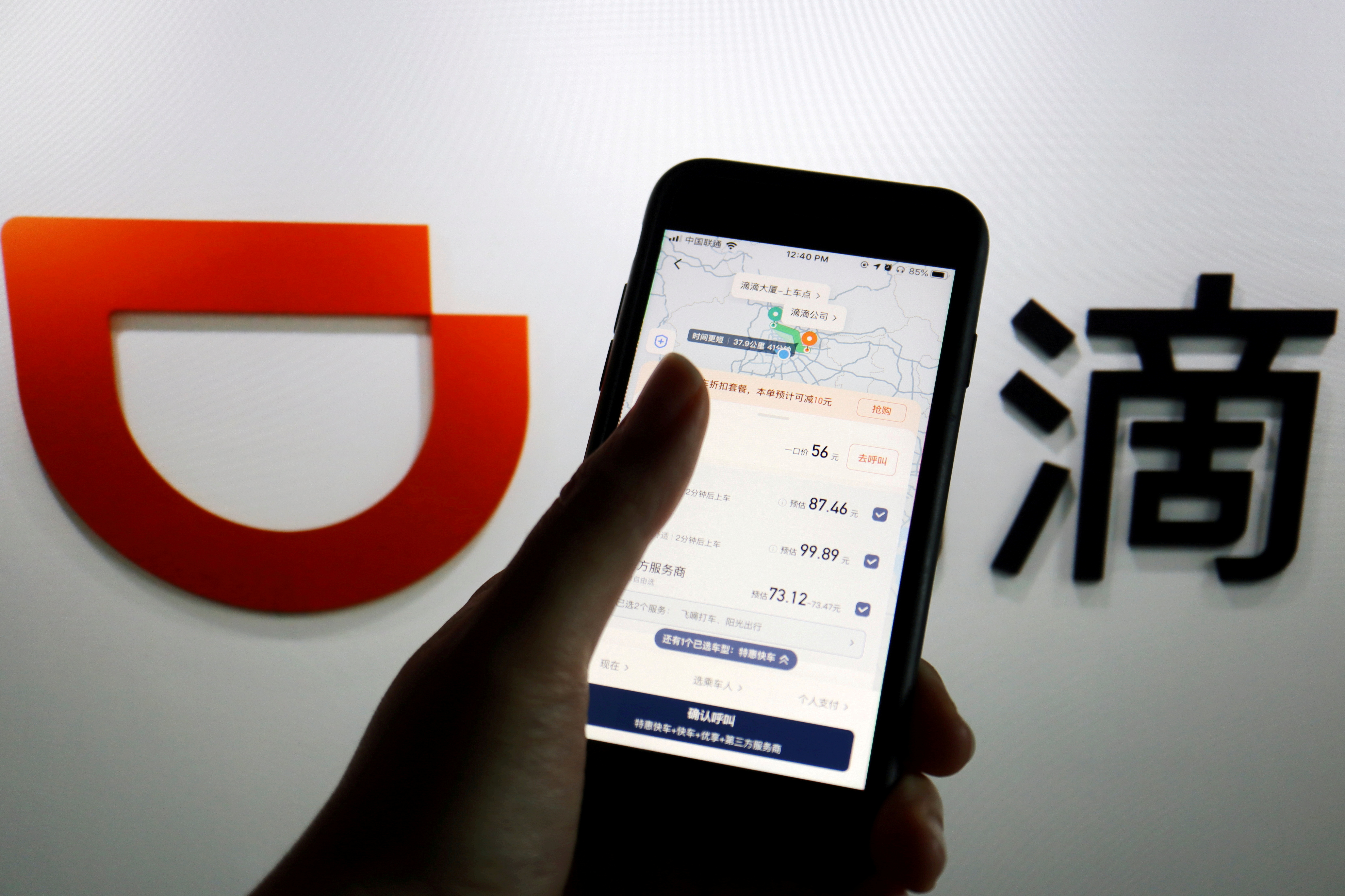 The app of Chinese ride-hailing giant Didi is seen on a mobile phone in front of the company logo displayed in this illustration picture taken July 1, 2021. REUTERS/Florence Lo/Illustration/File Photo