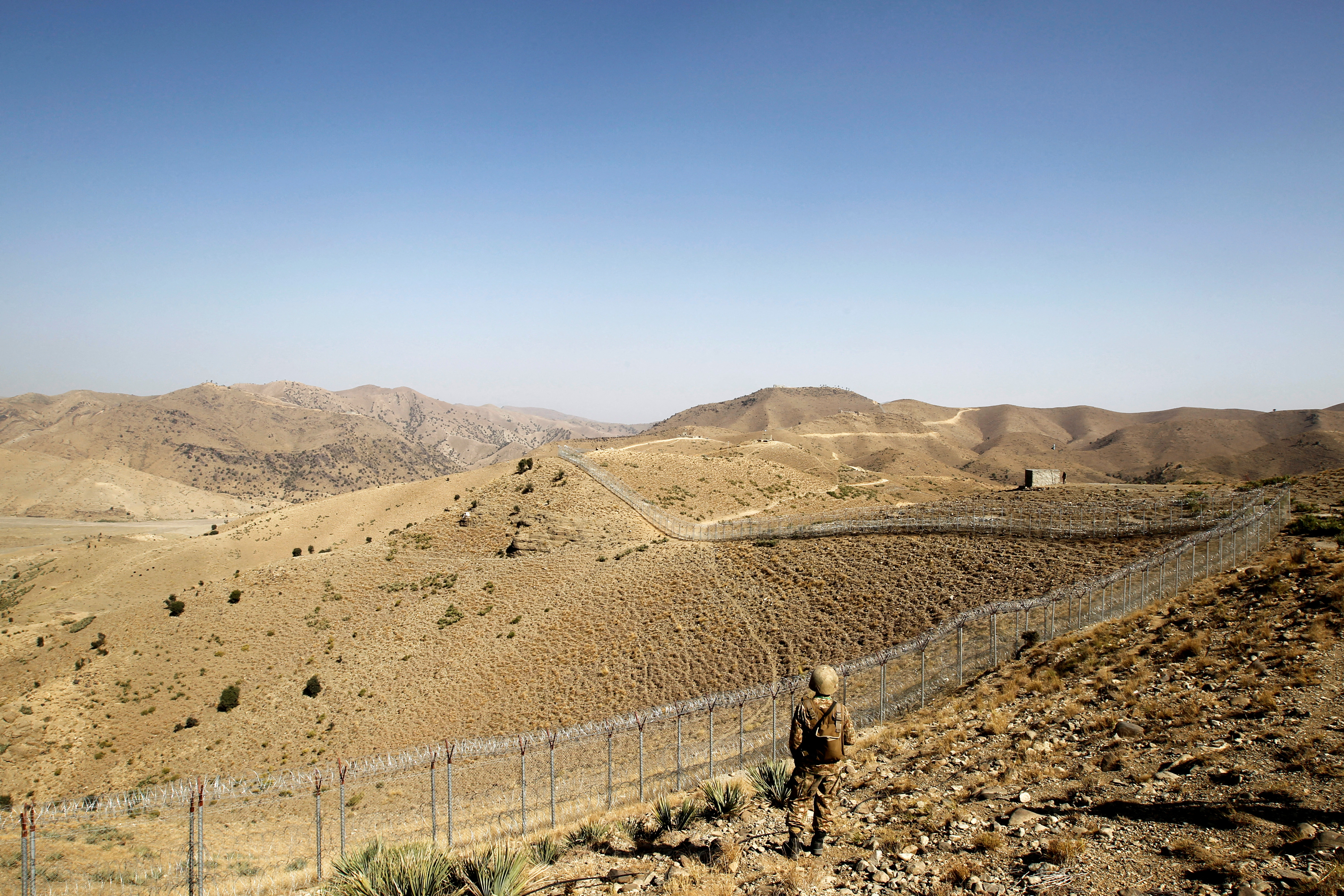 A soldier stands guard along the border fence outside the Kitton outpost on the border with Afghanistan in North Waziristan