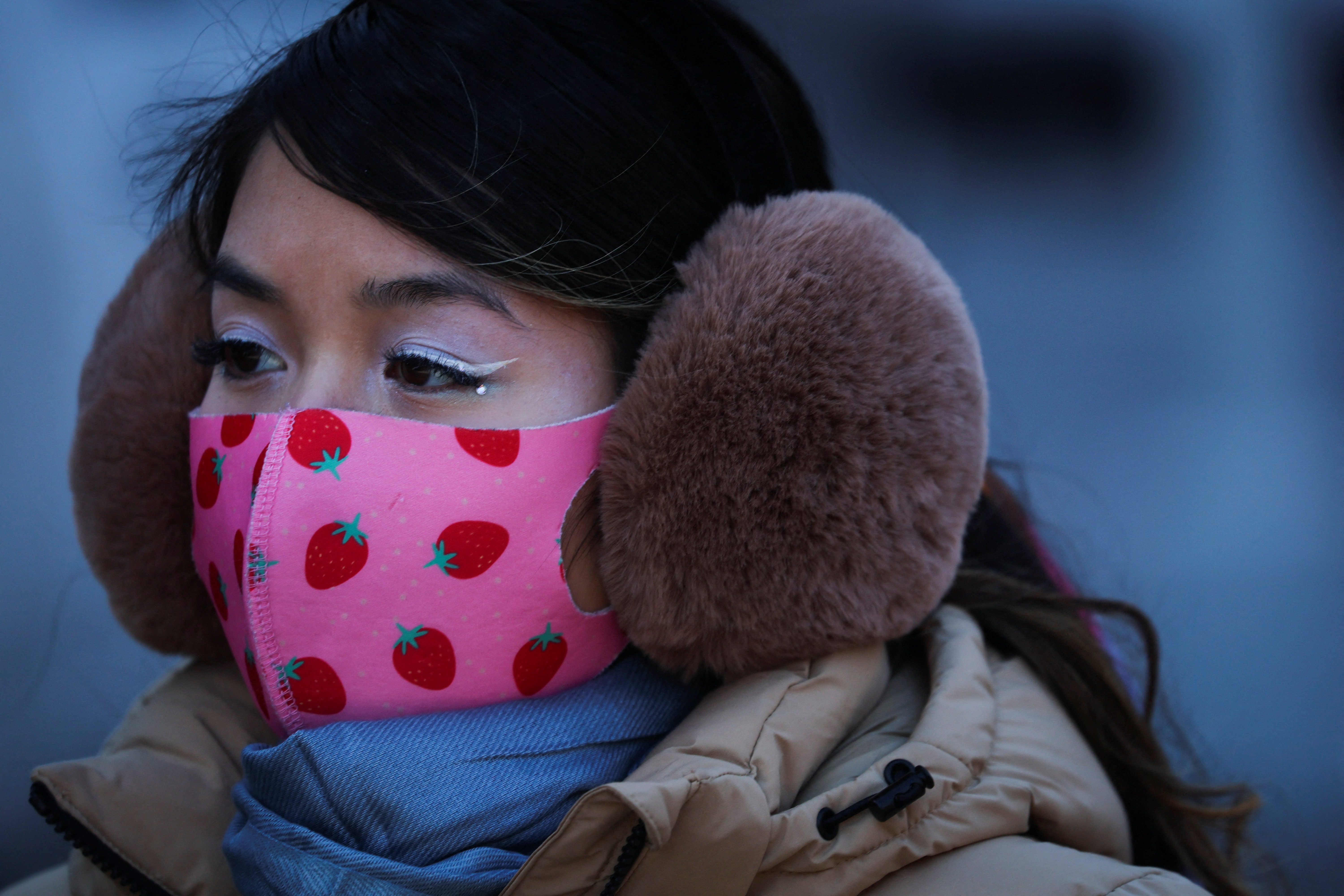 Woman wears a protective face mask and thick ear muffs during very cold temperatures in New York