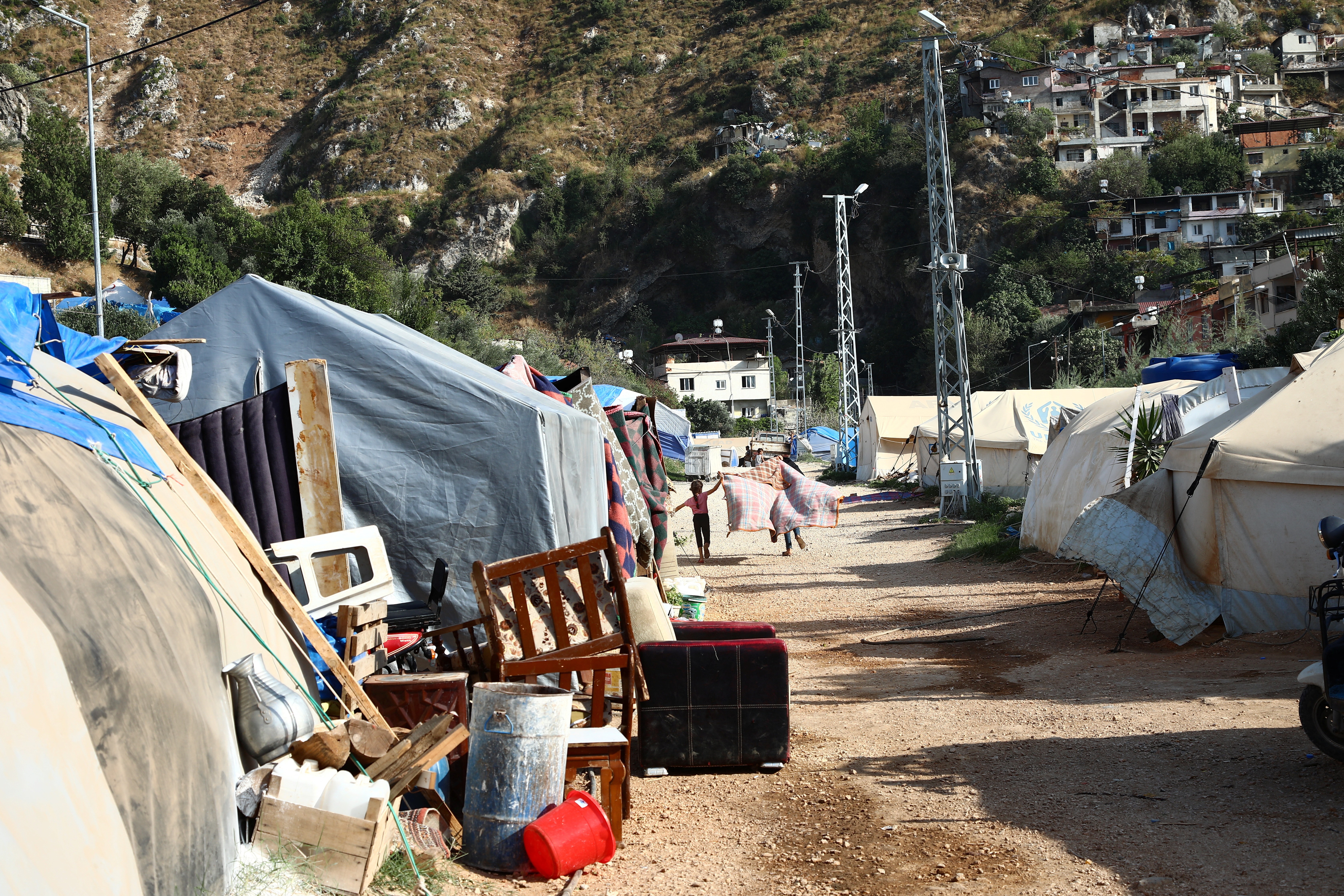 Children play between tents housing the earthquake survivors in Antakya