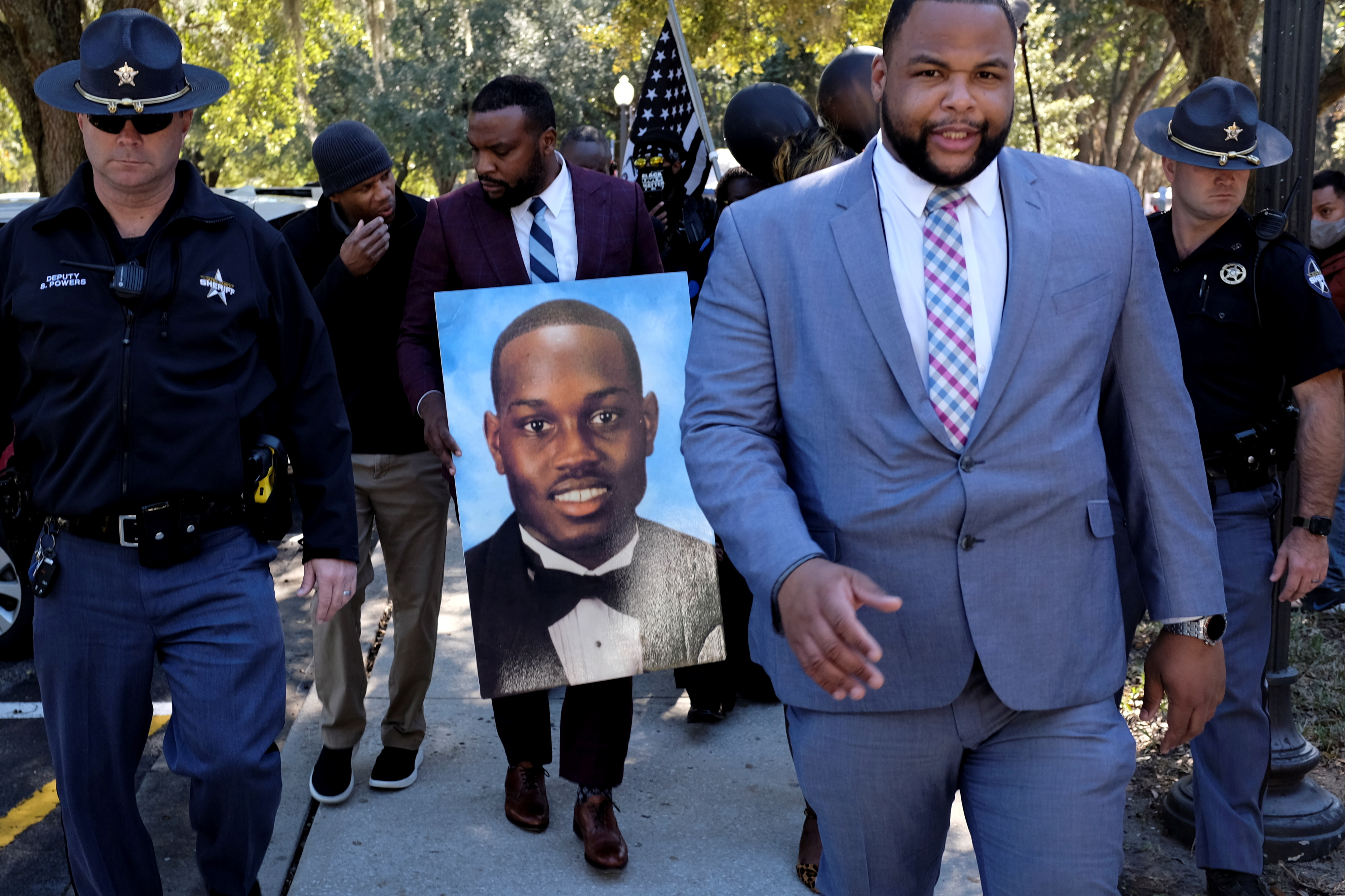 Attorney Lee Merritt holds a poster depicting Ahmaud Arbery as he leaves the Glynn County Courthouse in Brunswick, Georgia, U.S., November 23, 2021. REUTERS/Marco Bello 