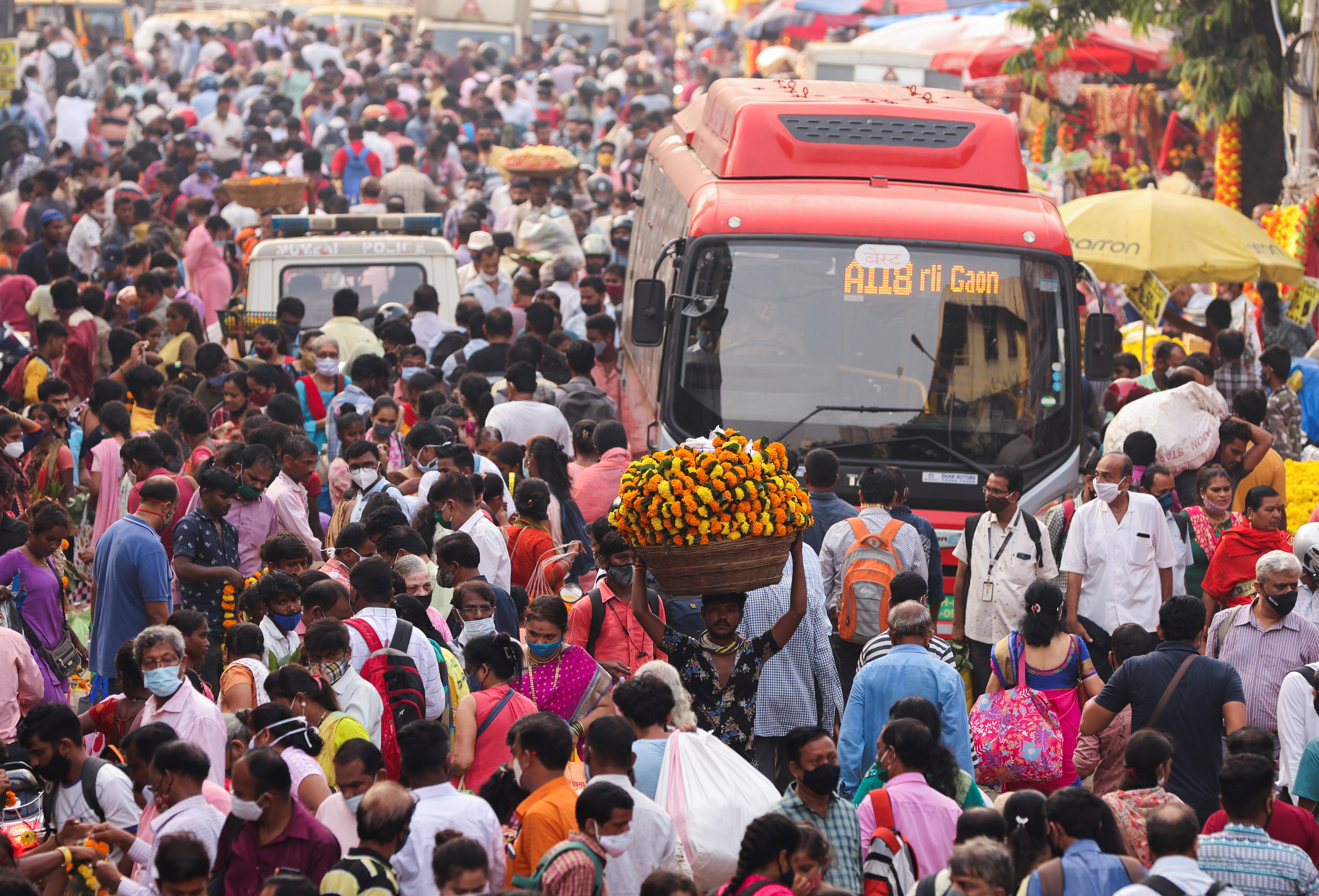 A man carrying flower garlands walks through a crowded market ahead of the religious festival of Dussehra, amidst the spread of the coronavirus disease (COVID-19) in Mumbai