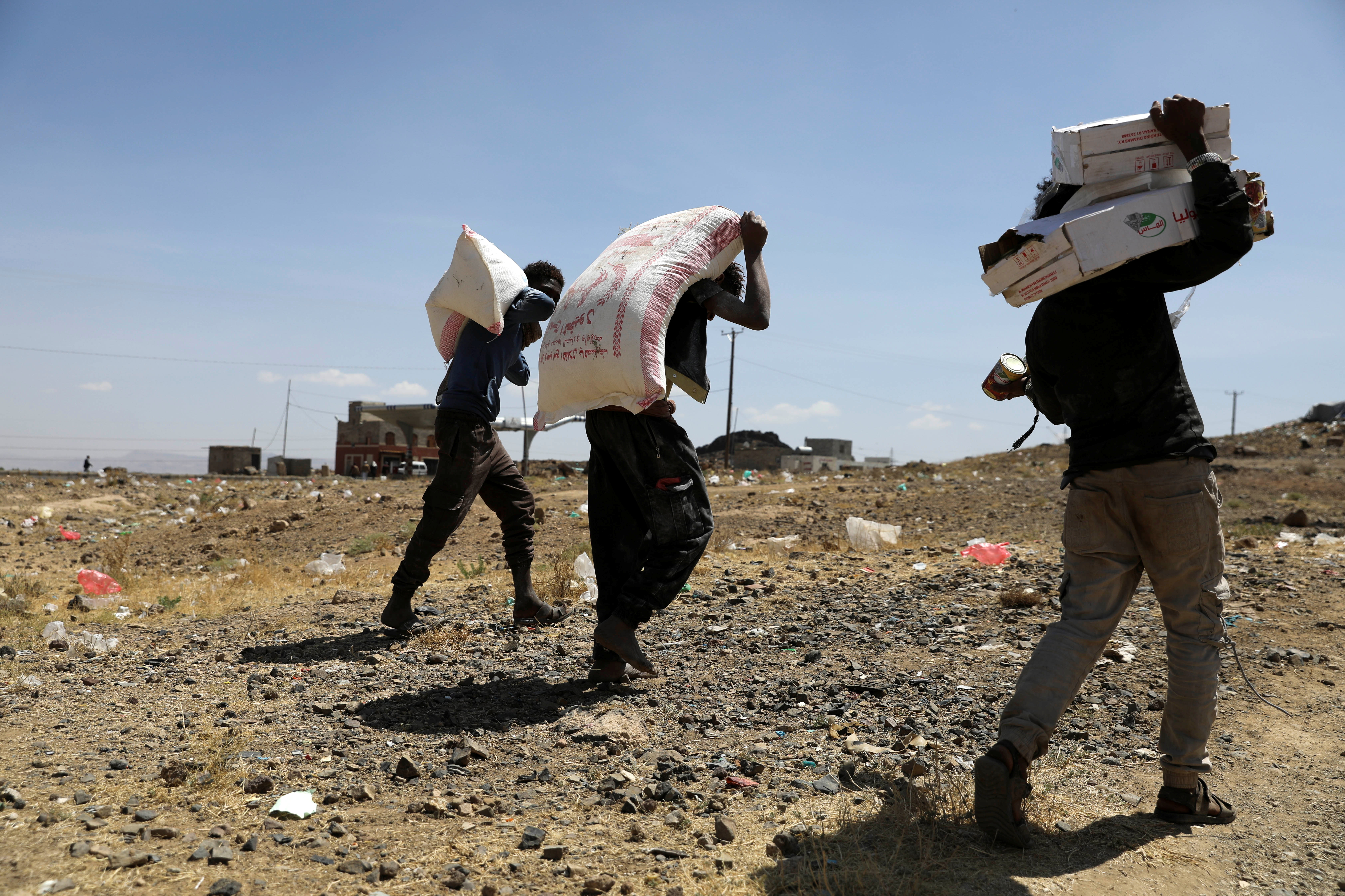 People carry foodstuff aid they received from the local charity Mona Relief at a camp for internally displaced people on the outskirts of Sanaa