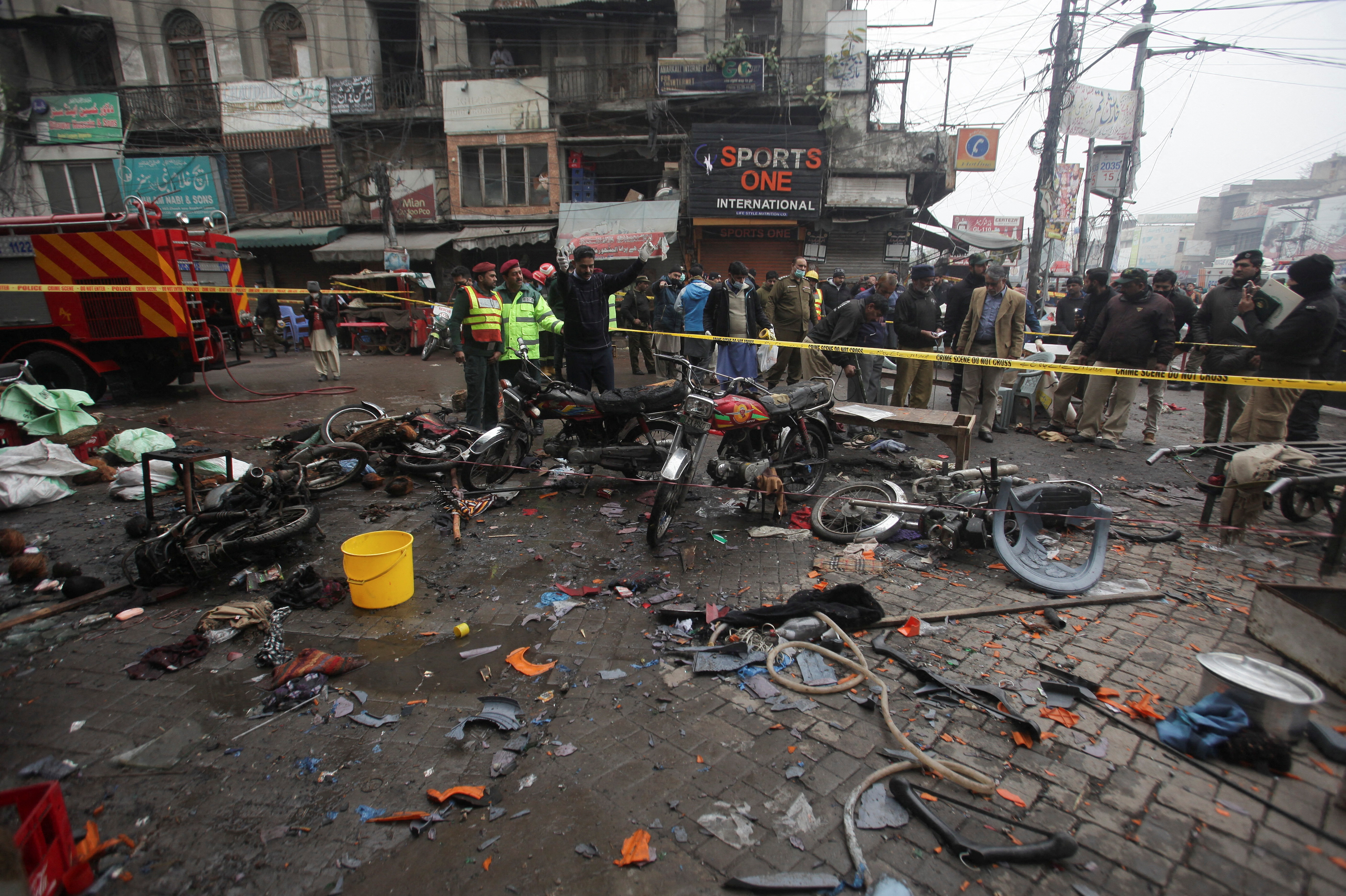 Members of crime scene unit and a bomb disposal unit survey the site after a blast in a market, in Lahore