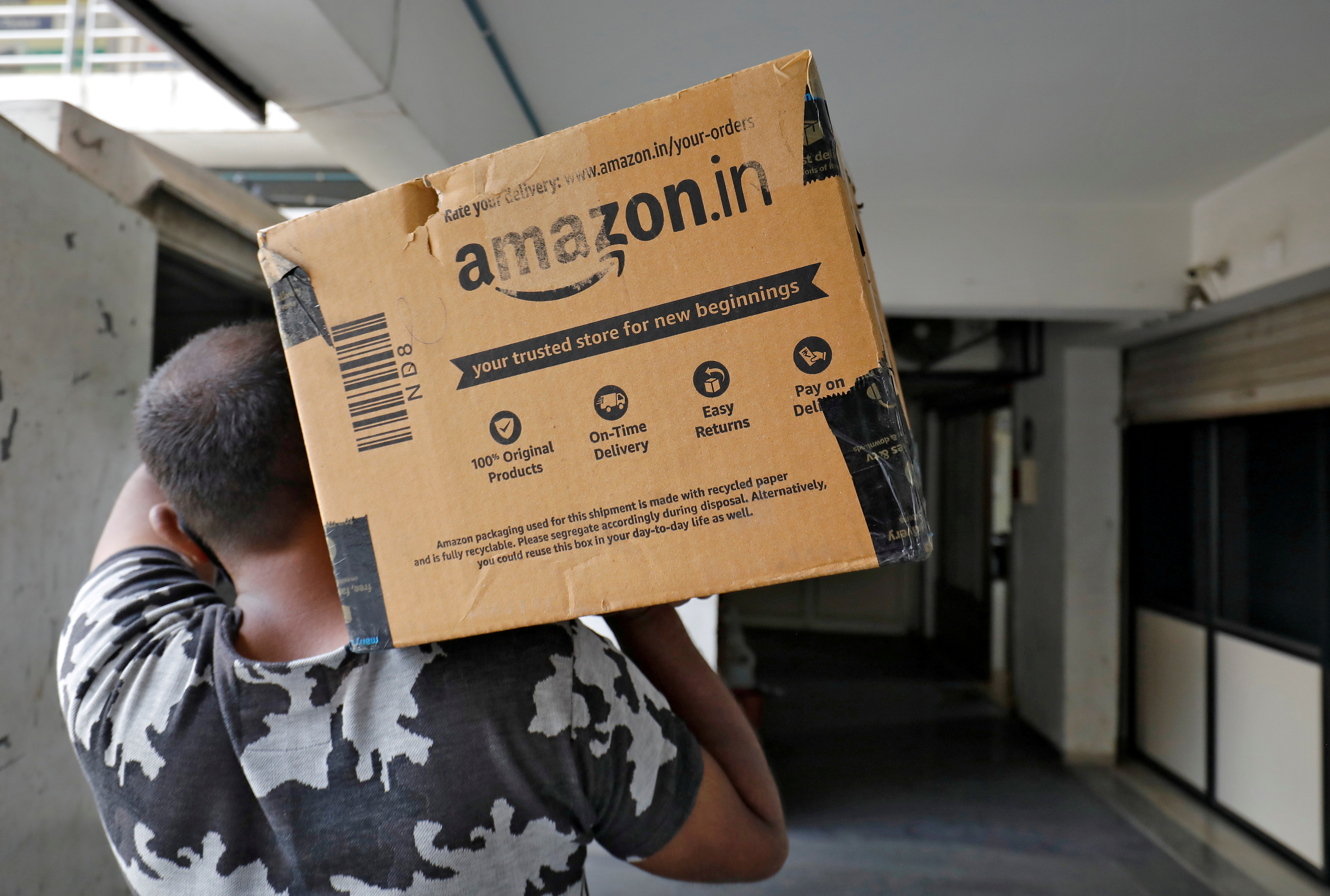 A delivery worker carries an Amazon package in Ahmedabad