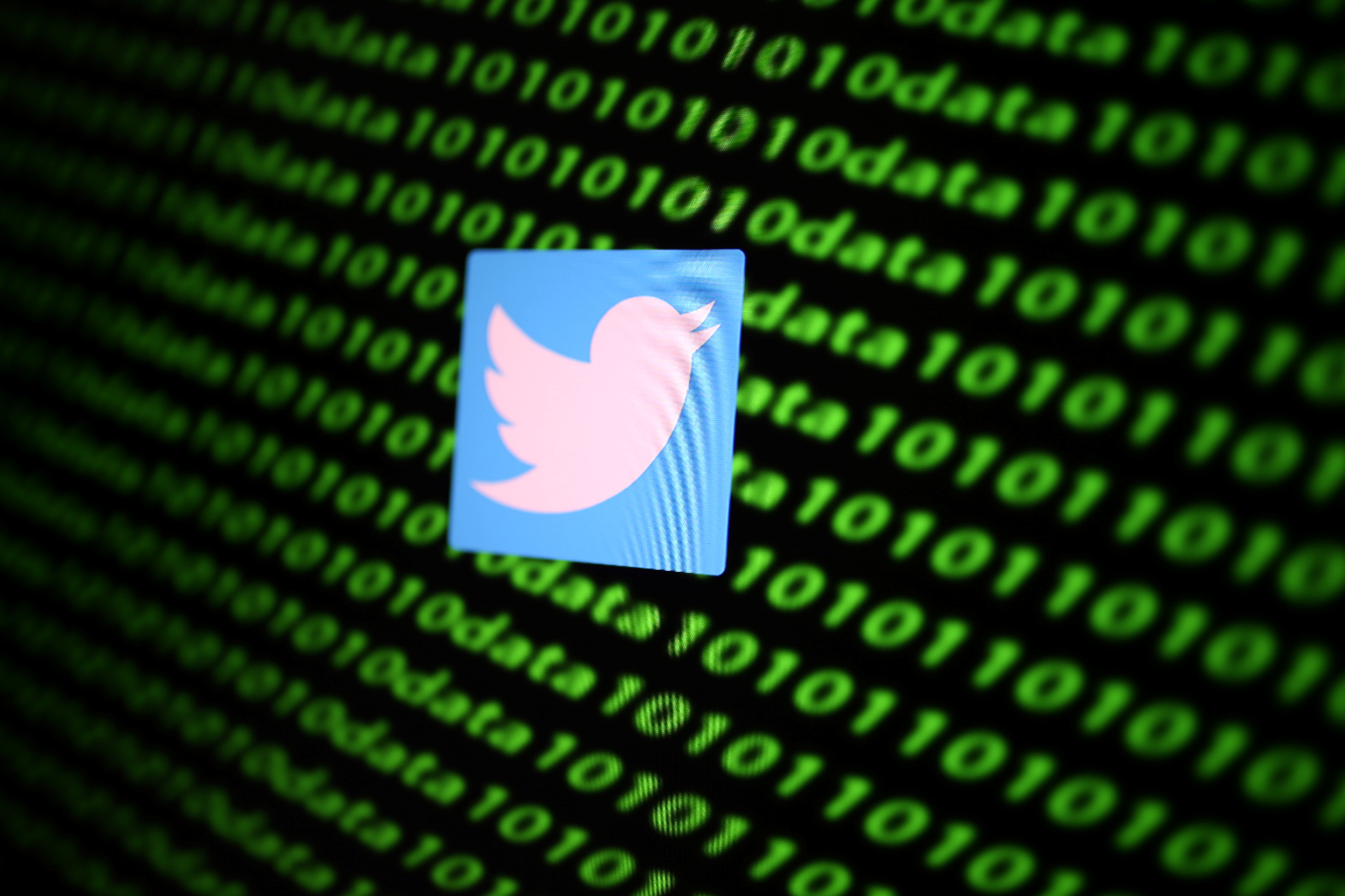 The Twitter logo and binary cyber codes are seen in this illustration