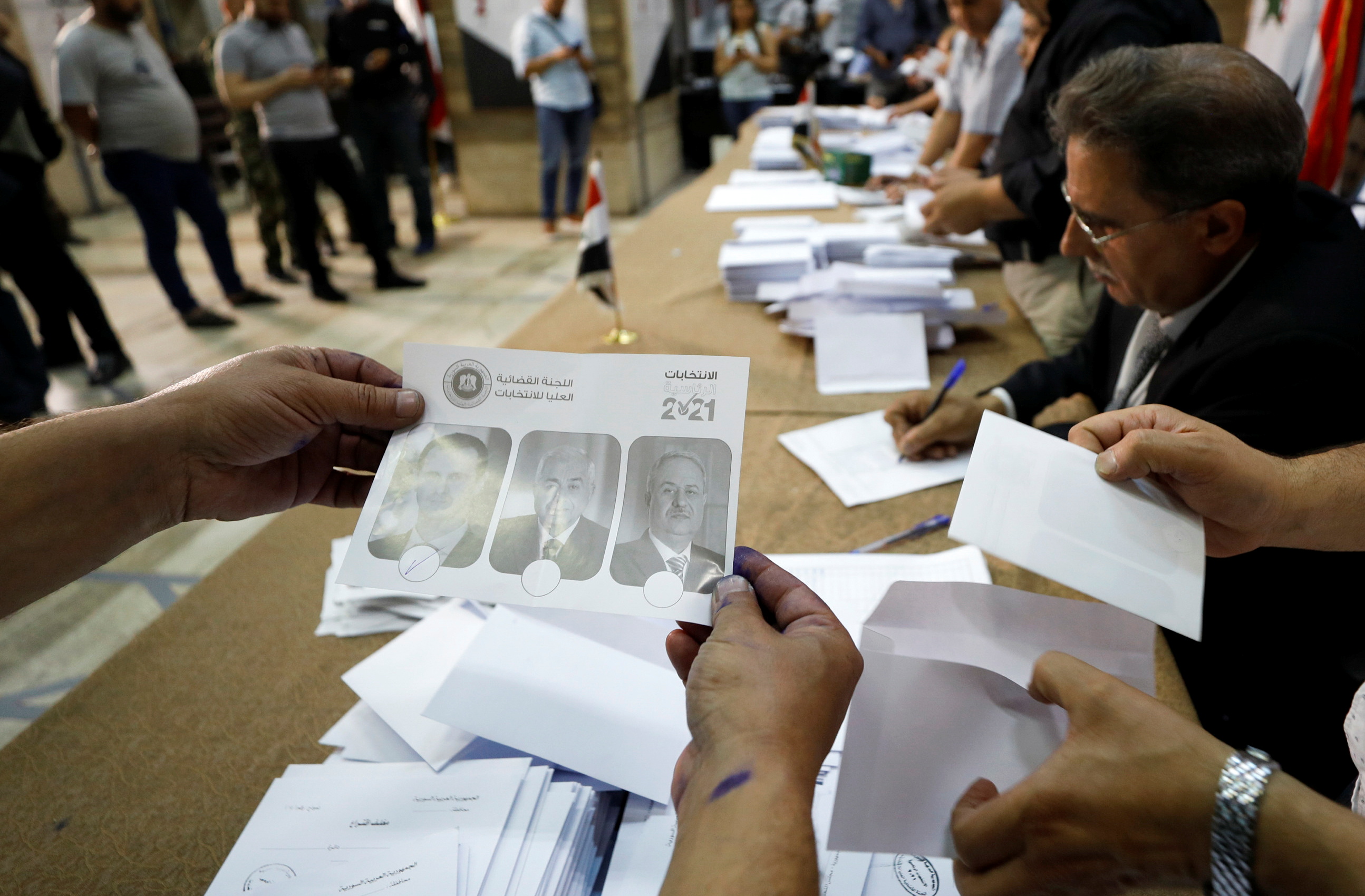 Poll workers count ballots after polls closed during the country's presidential elections in Damascus