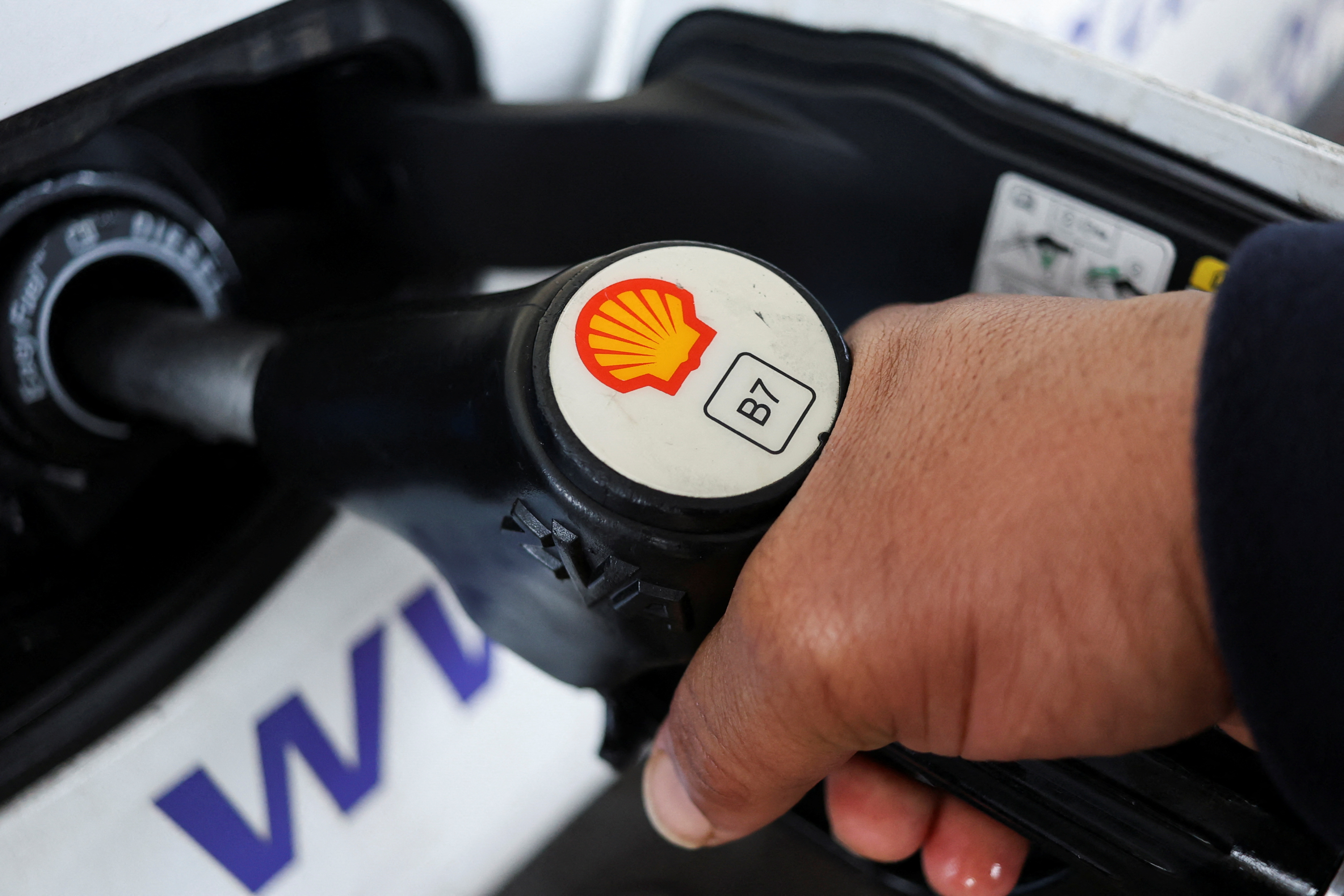 A man holds a nozzle with Shell's logo at a petrol station in South East London,