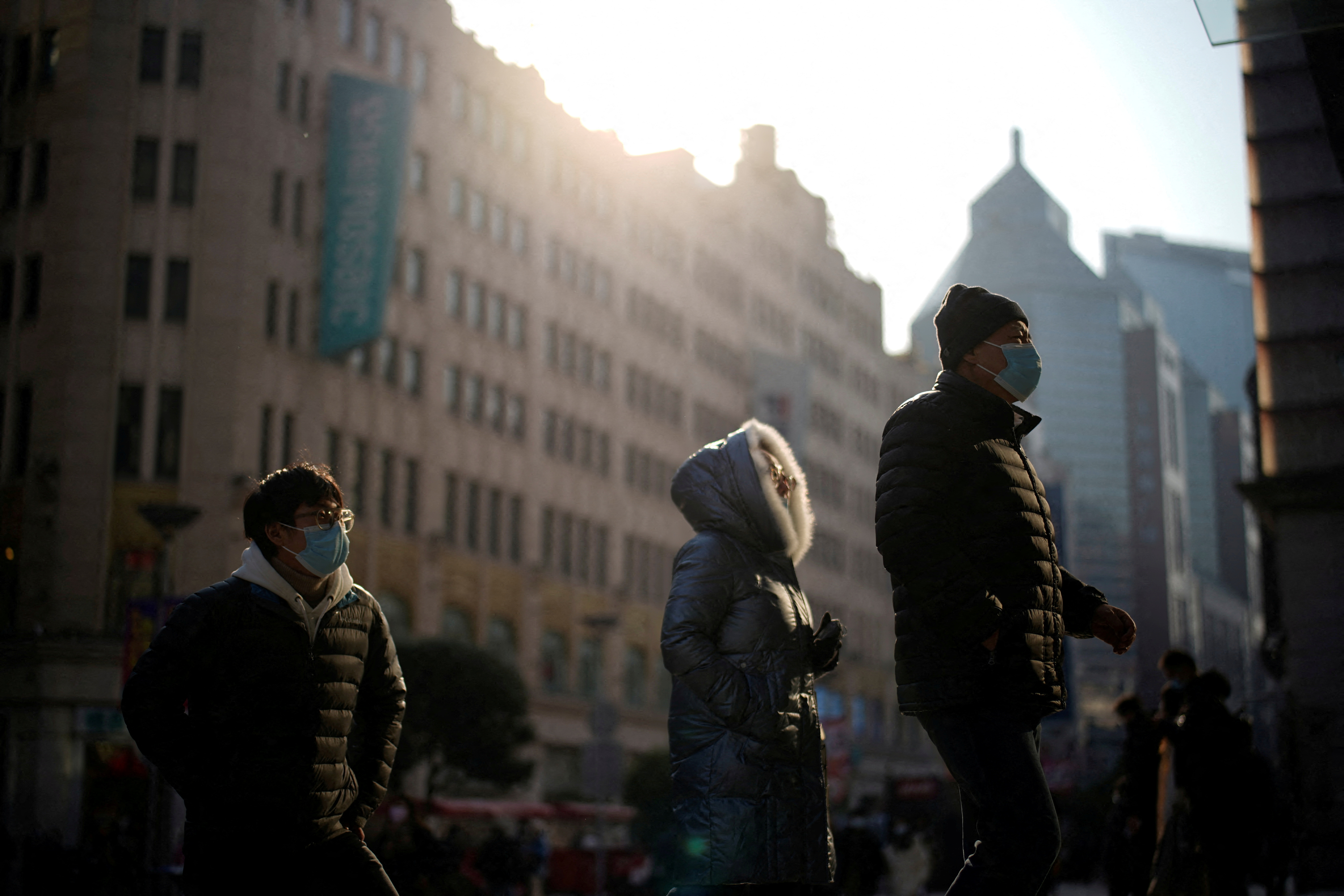 People wearing protective face masks walk on a street, following new cases of the coronavirus disease (COVID-19), in Shanghai, China, December 30, 2021. REUTERS/Aly Song