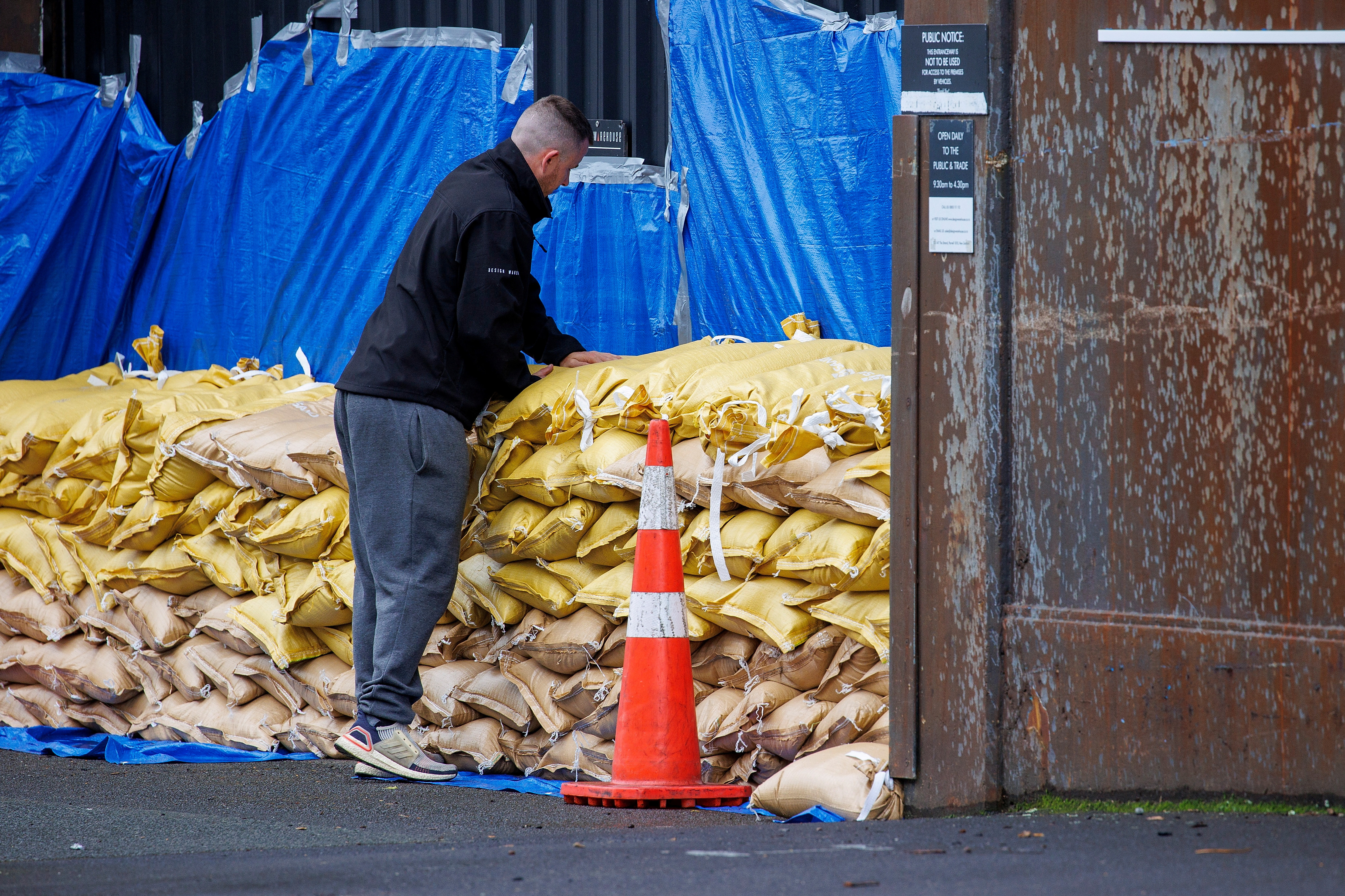 A man stacks up sandbags to protect a warehouse before the arrival of Cyclone Gabriele in Auckland