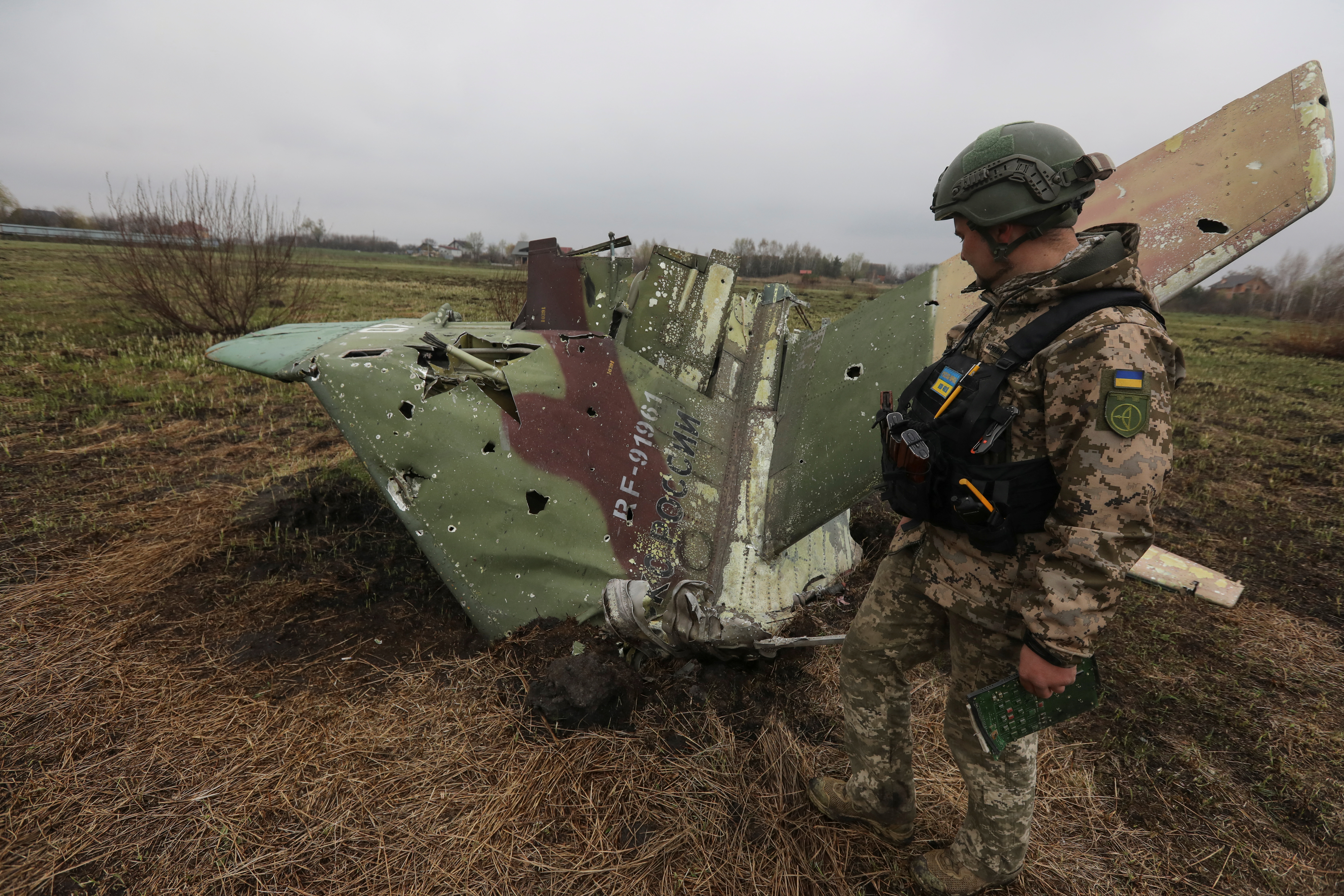 A military sapper inspects remains of a Russian Sukhoi Su-25 fighting aircraft hit by Ukrainian Armed Forces during Russia's invasion in Kyiv Region