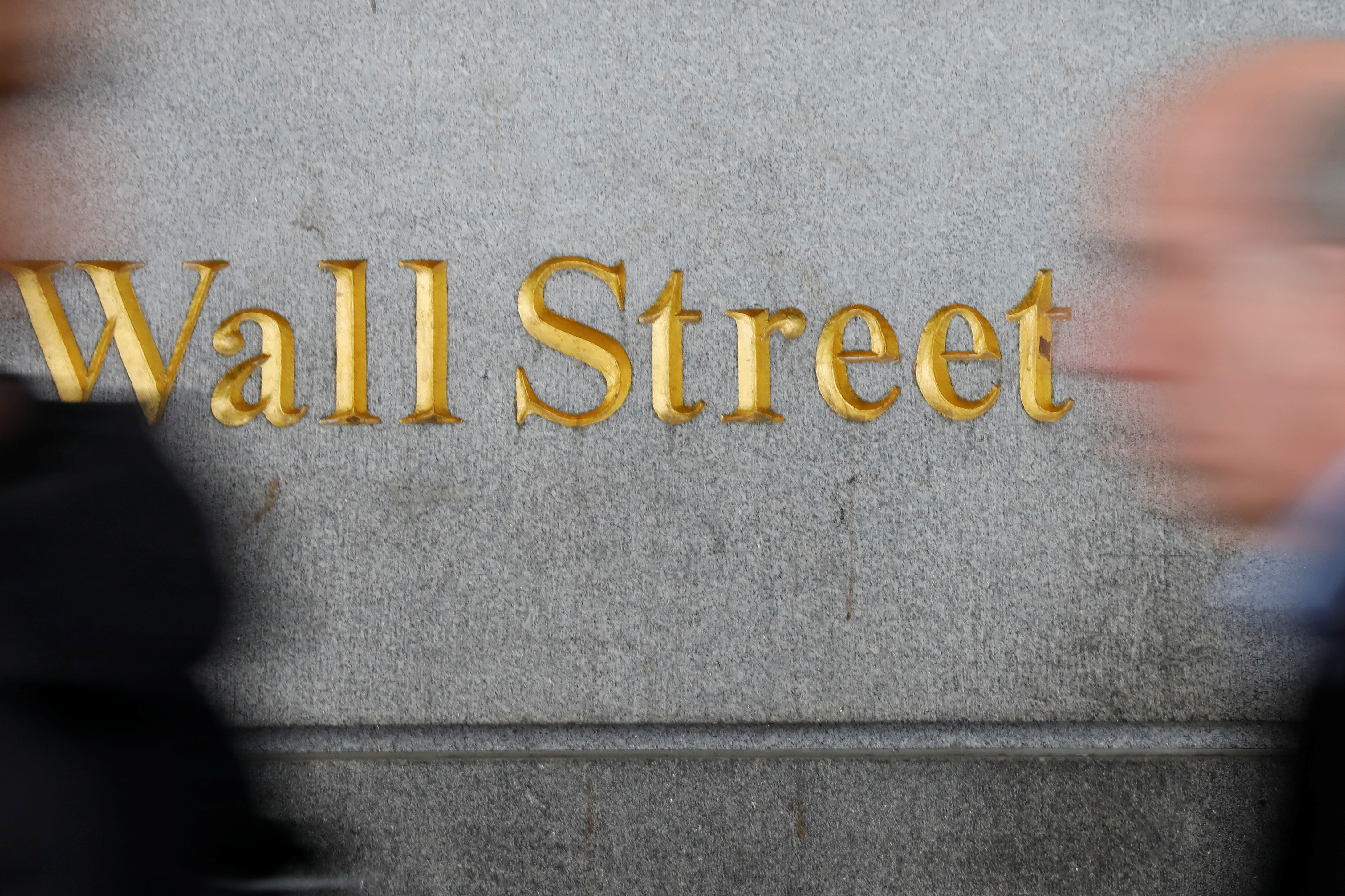 People walk by a Wall Street sign close to the NYSE in New York
