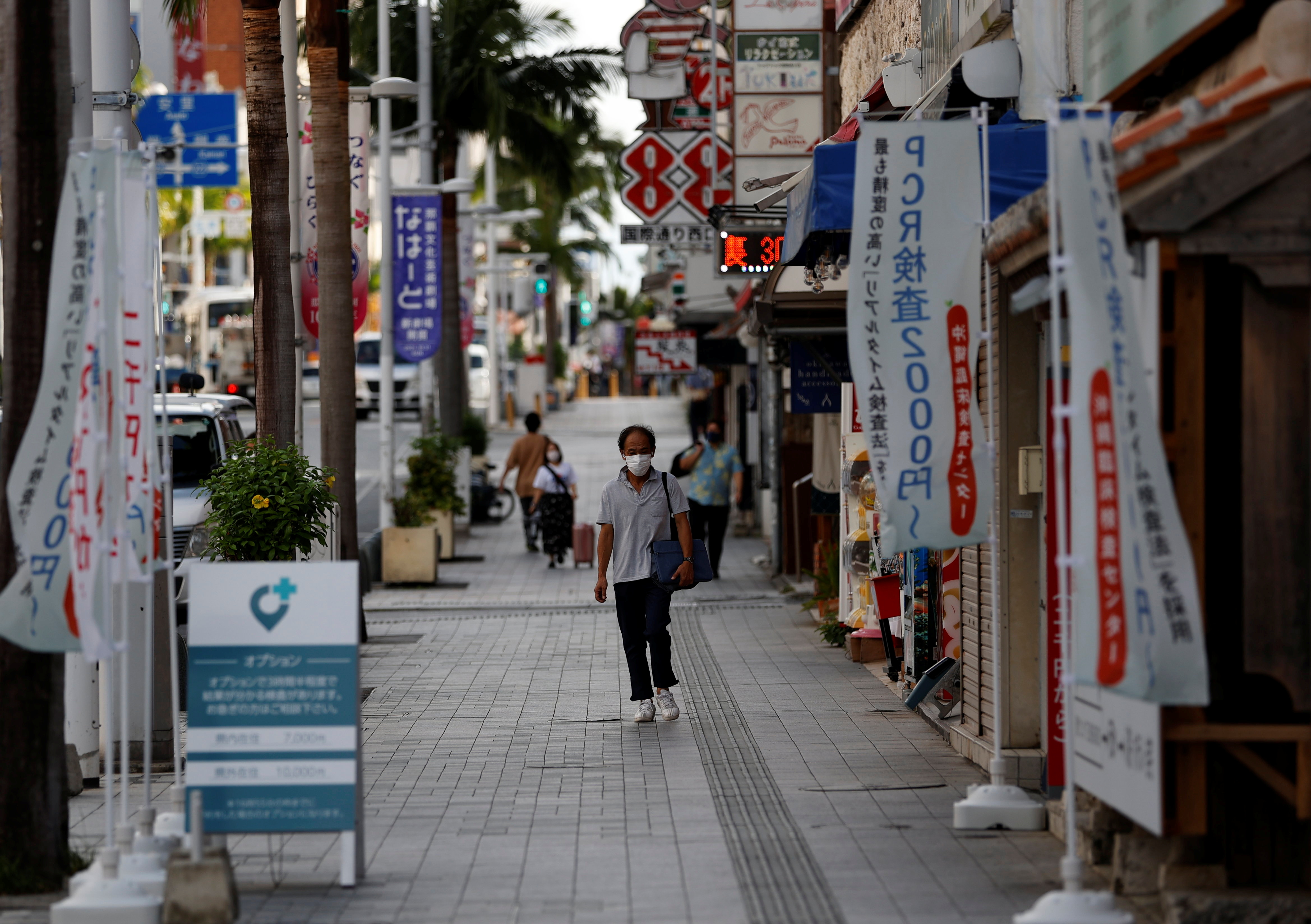 People wearing protective face masks, amid the coronavirus disease (COVID-19) pandemic, walk along the Kokusai-dori in the prefectural capital Naha, Okinawa
