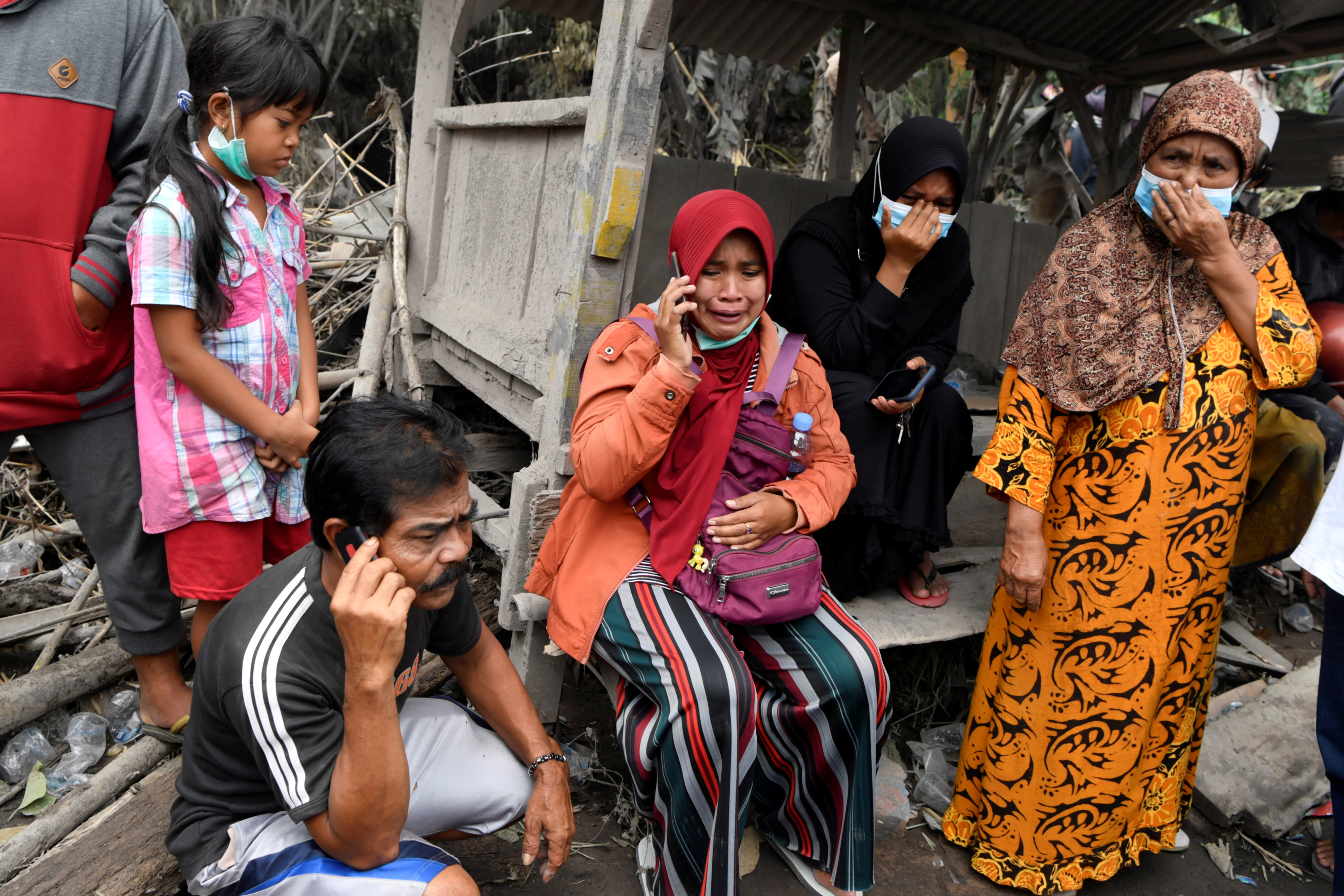 Families of the victims of the Mount Semeru volcano eruption react as they wait for information in Sumber Wuluh