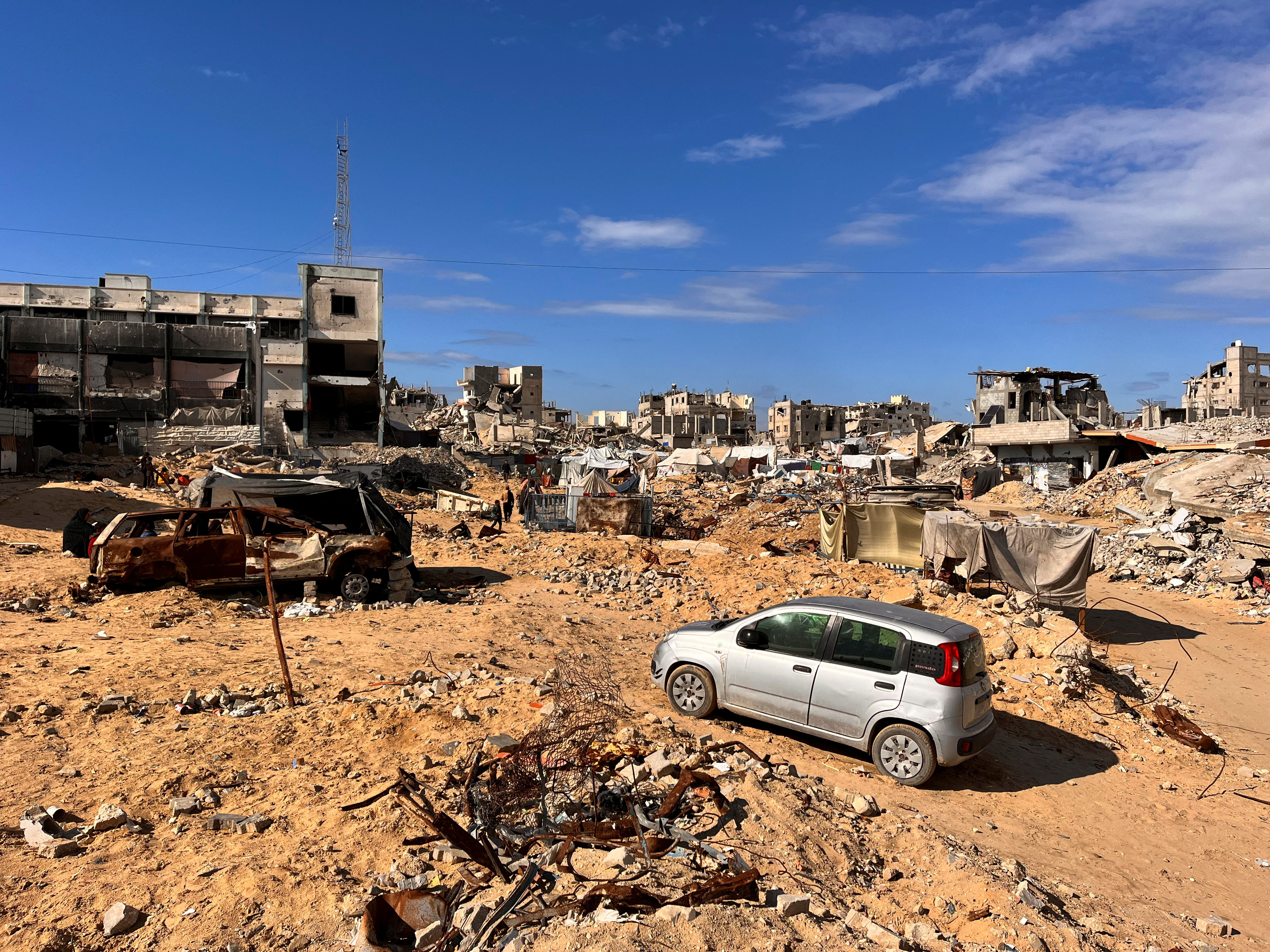 Palestinians walk through a damaged site in Khan Younis