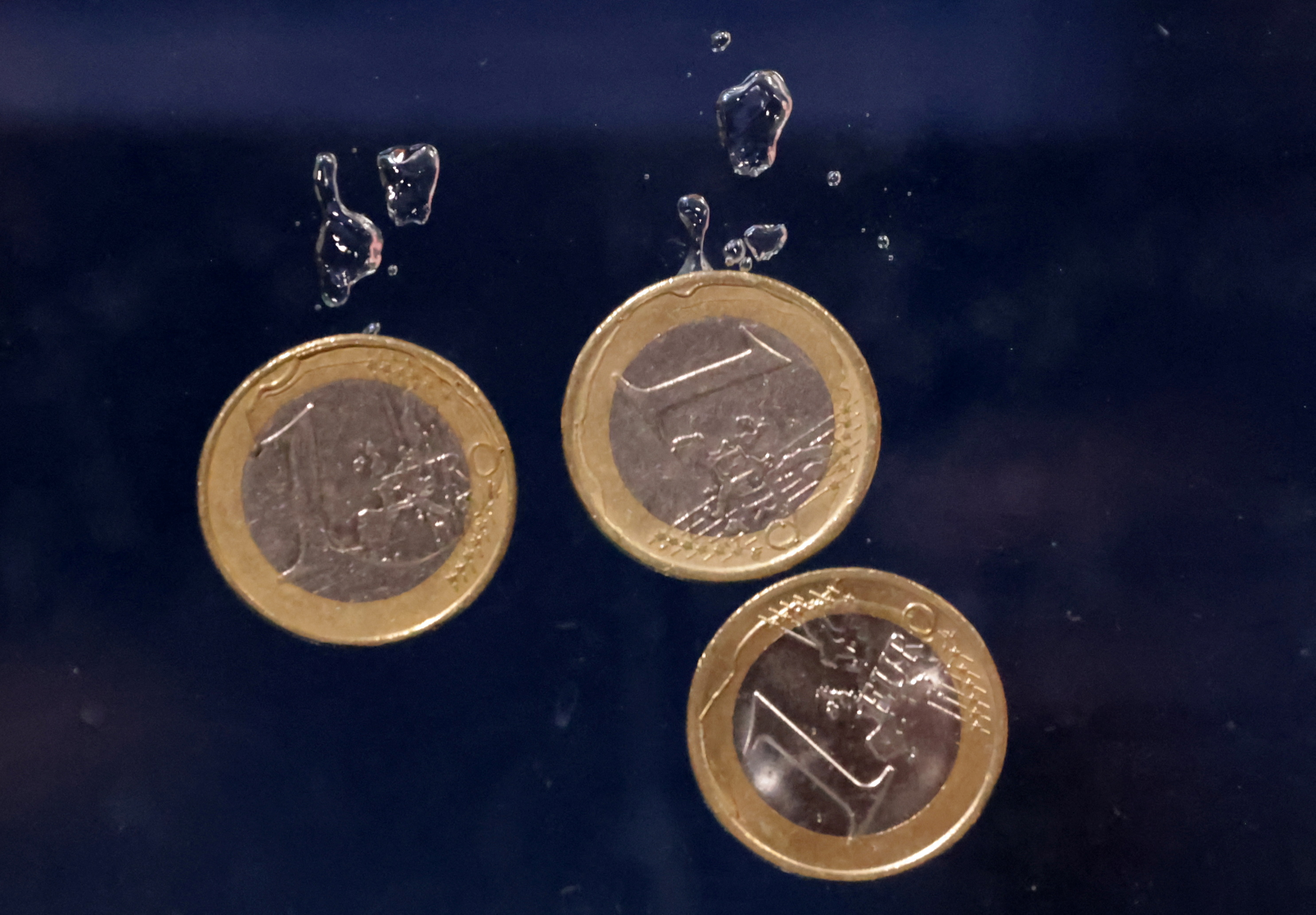 Illustration shows Euro coins plunging into water