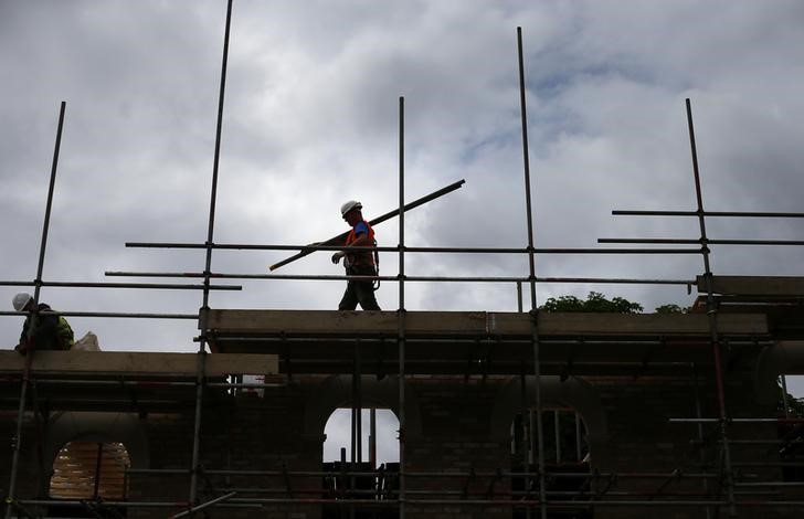 A builder assembles scaffolding as he works on new homes in south London