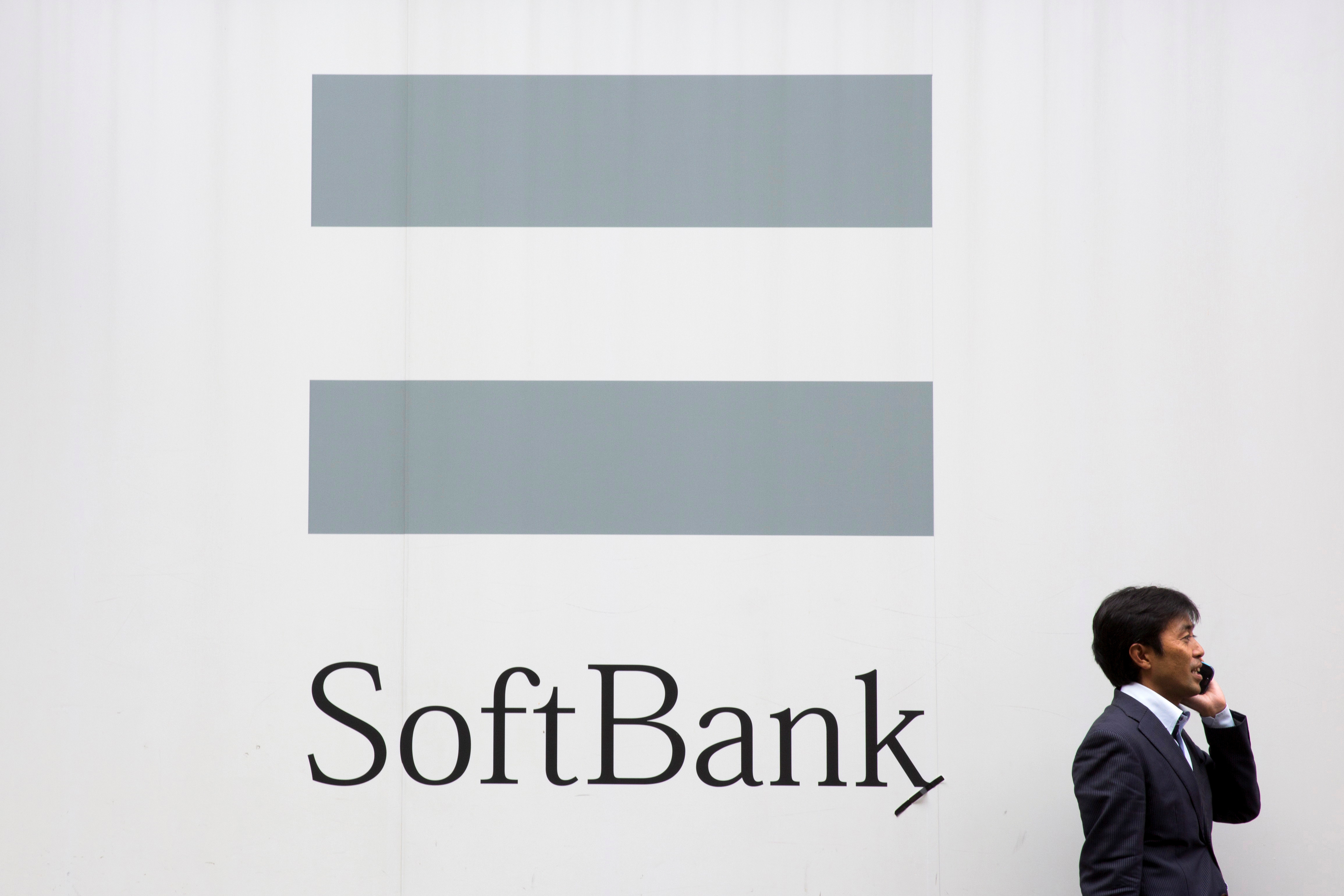 A man talks on the phone as he stand in front of an advertising poster of the SoftBank telecommunications company in Tokyo
