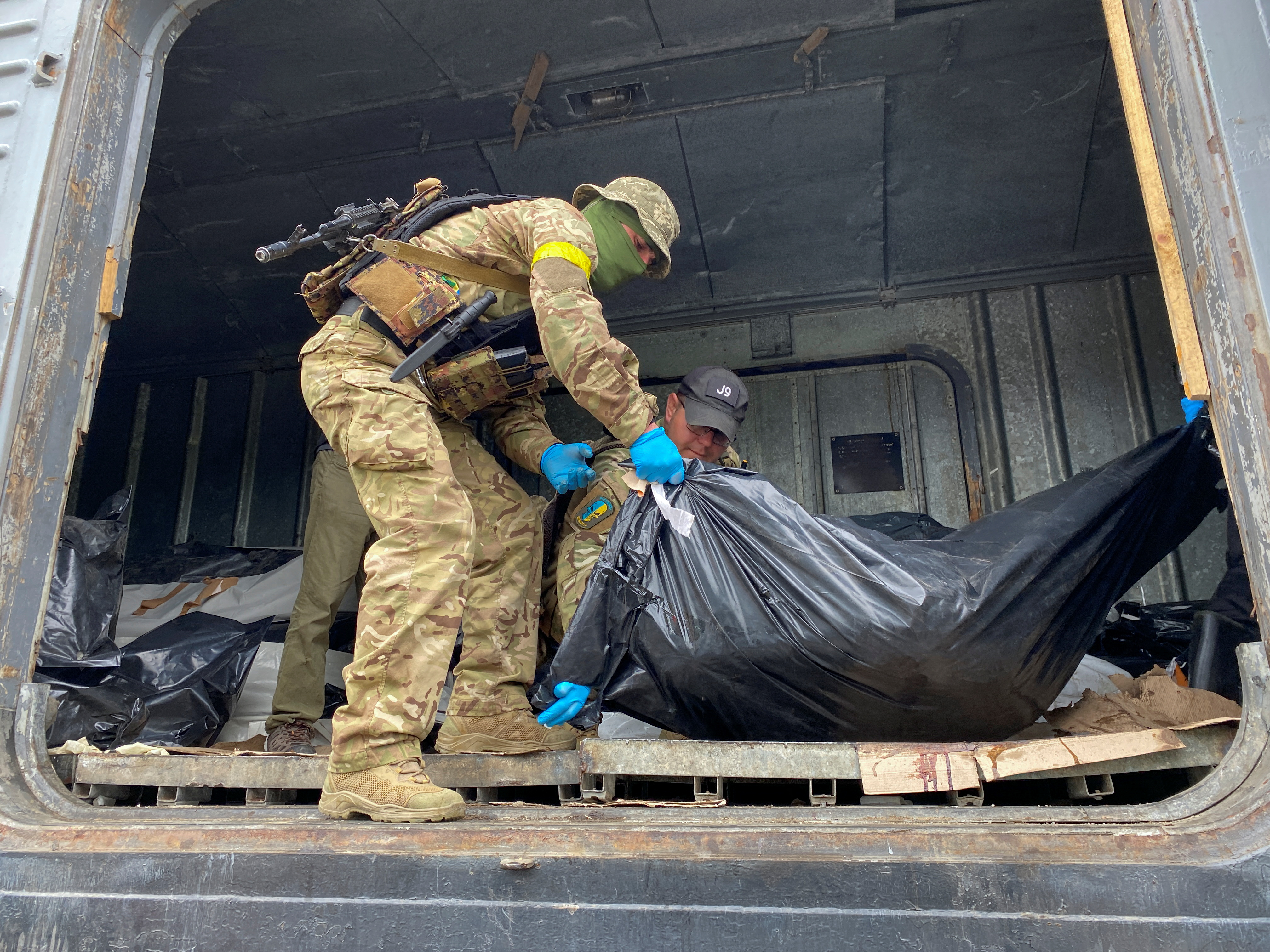 Ukrainian servicemen load bodies of killed Russian soldiers to refrigerated rail car, in Kharkiv