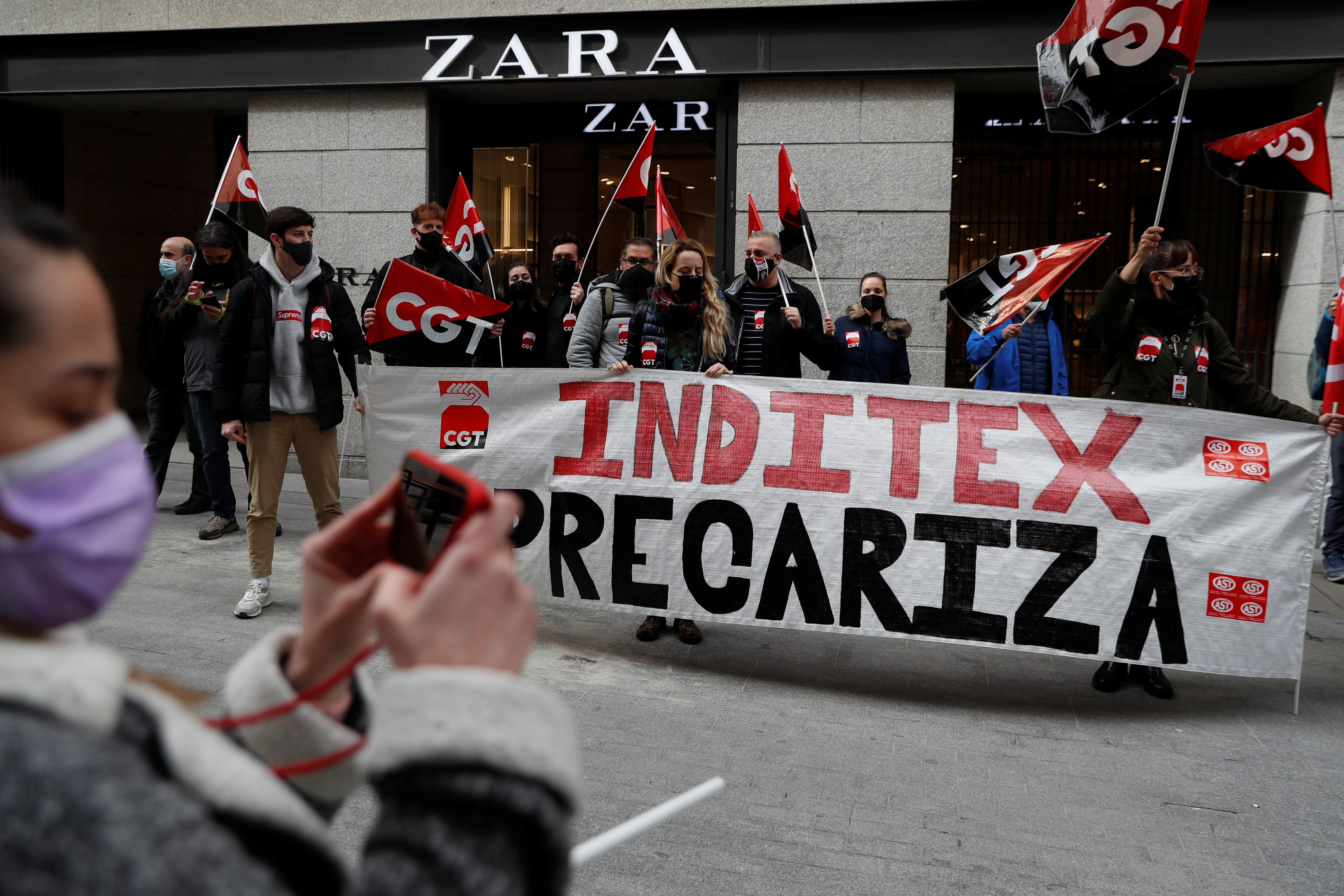 People hold flags from Spain's CGT labour union as they protest outside a Zara clothing store, an Inditex brand,  in Madrid, Spain, February 25, 2021. The banner reads: 