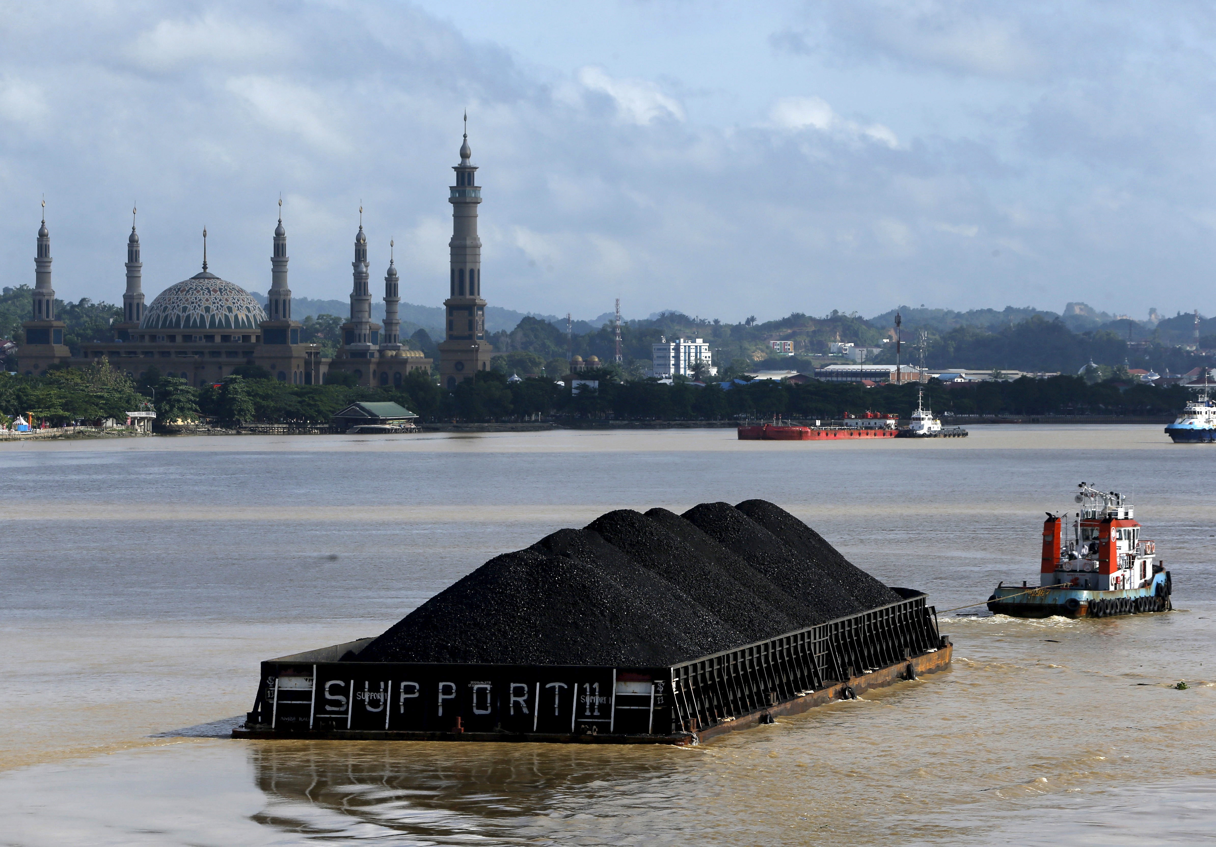 FILE PHOTO:A tug boat pulls a coal barge along the Mahakam River in Samarinda