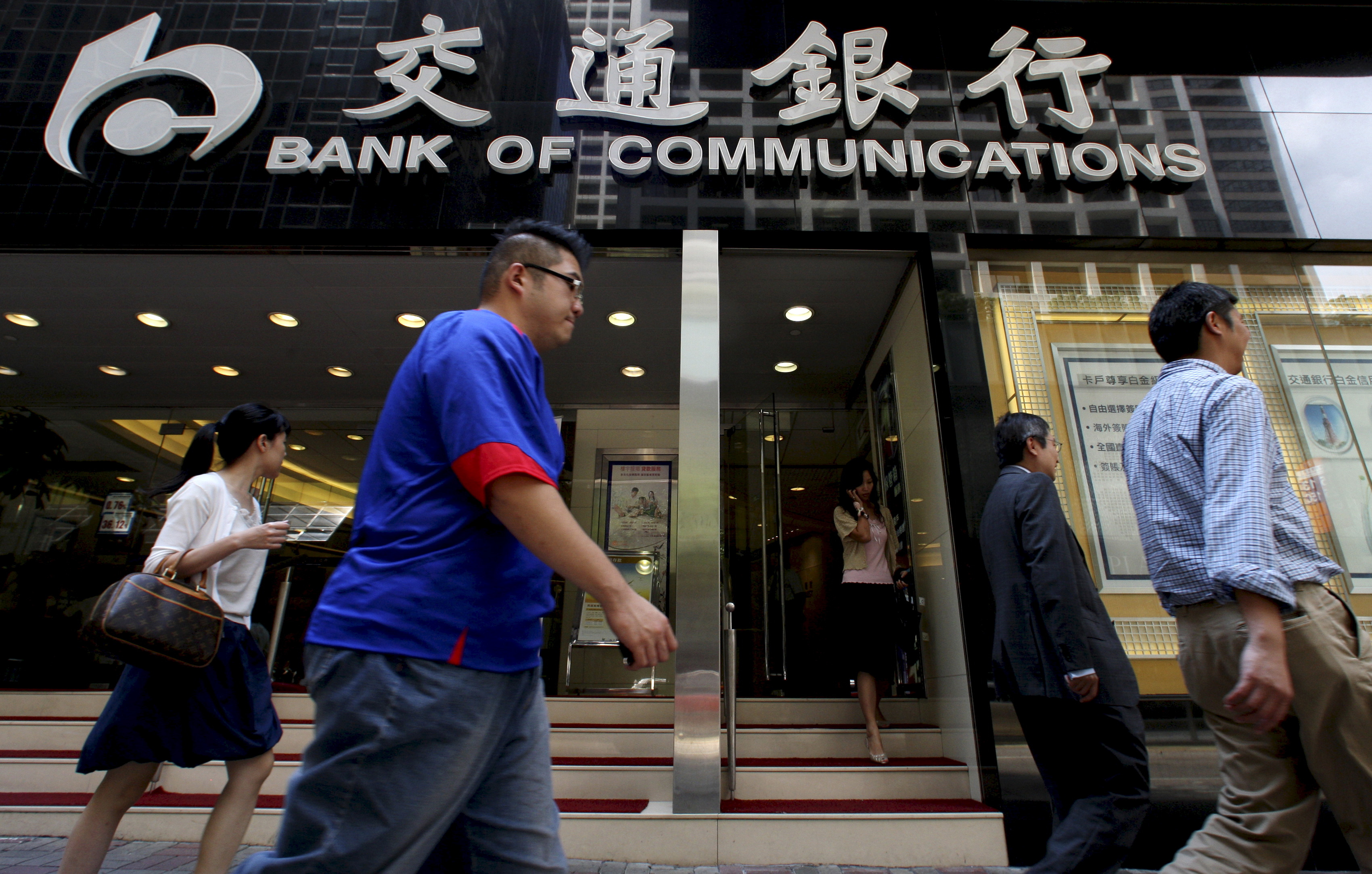 People walk past the Bank of Communications at its central branch in the financial district of Hong Kong