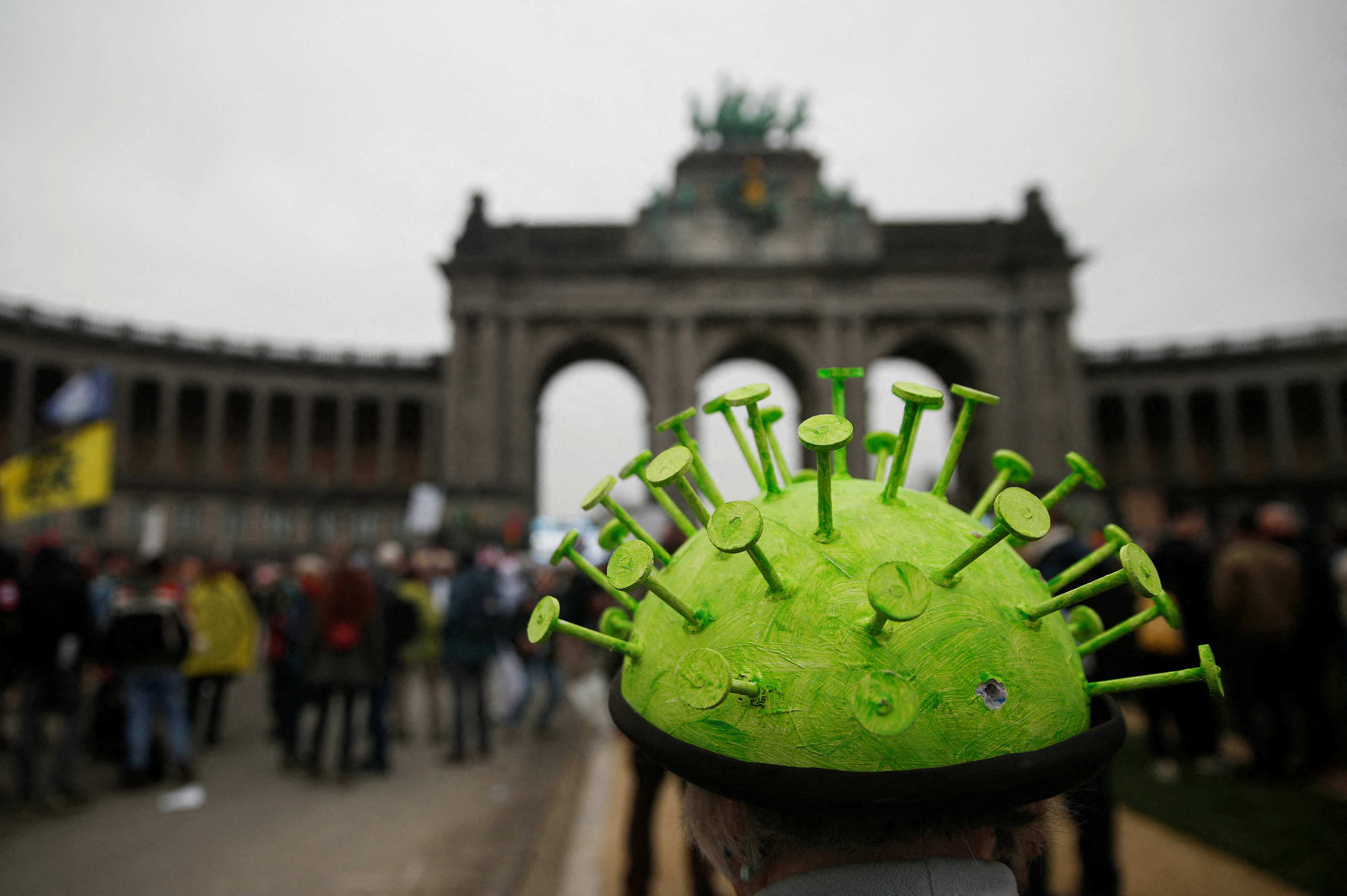 En person bär en hatt som föreställer en viruspartikel vid en demonstration mot den belgiska regeringens restriktioner som införts för att begränsa spridningen av coronaviruset (COVID-19) i Bryssel, Belgien, 23 januari 2022. REUTERS/Johanna Geron