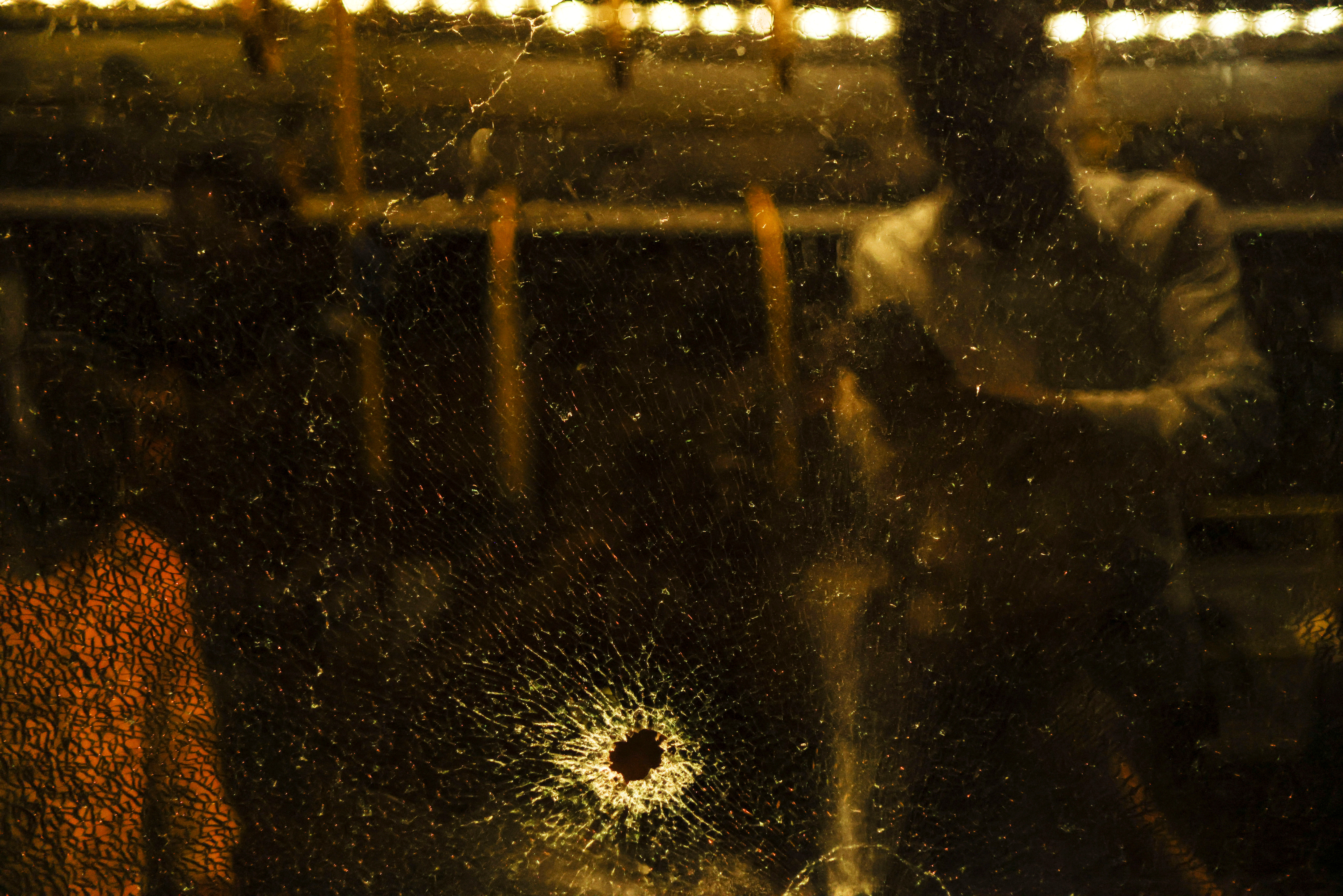 A man stands behind a shattered window of a bus following an incident in Jerusalem