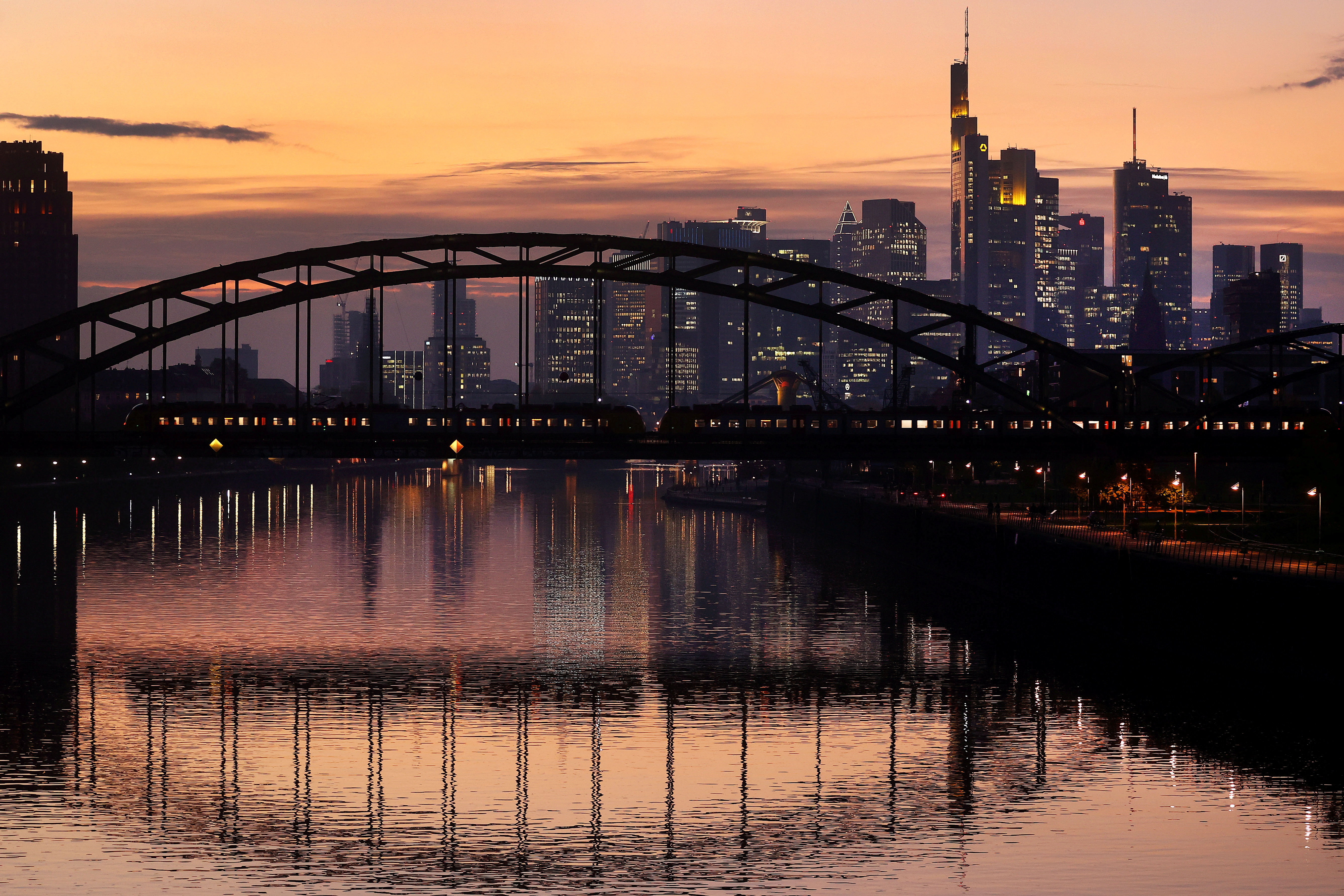 A commuter train passes by the skyline of the financial district in Frankfurt