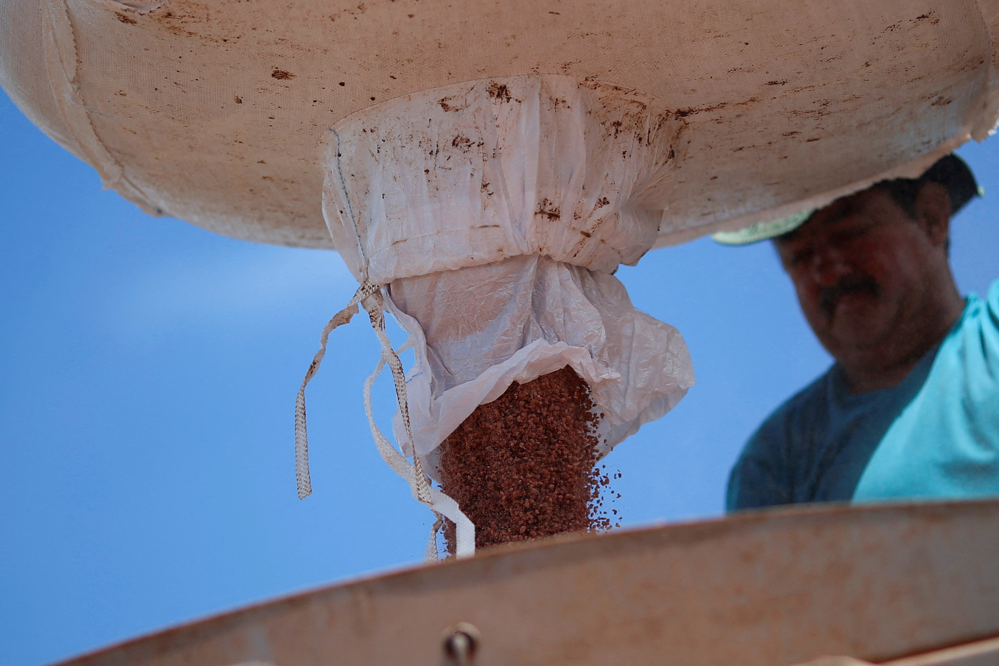 FILE PHOTO: An agricultural worker is seen loading a tractor with fertilizer before spreading it in a soybean field, near Brasilia