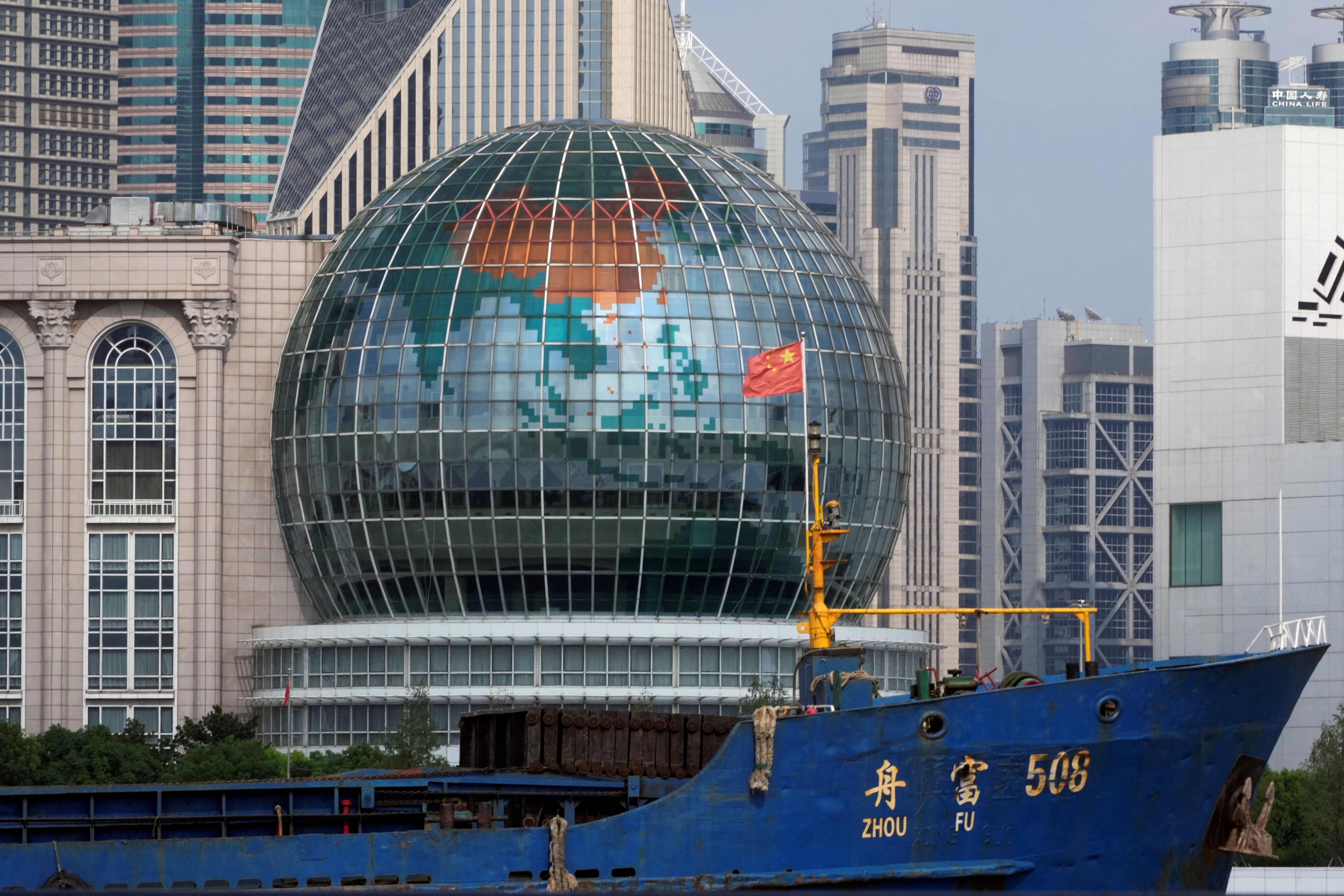 Chinese flag flutters on a ship in front of a globe in Shanghai