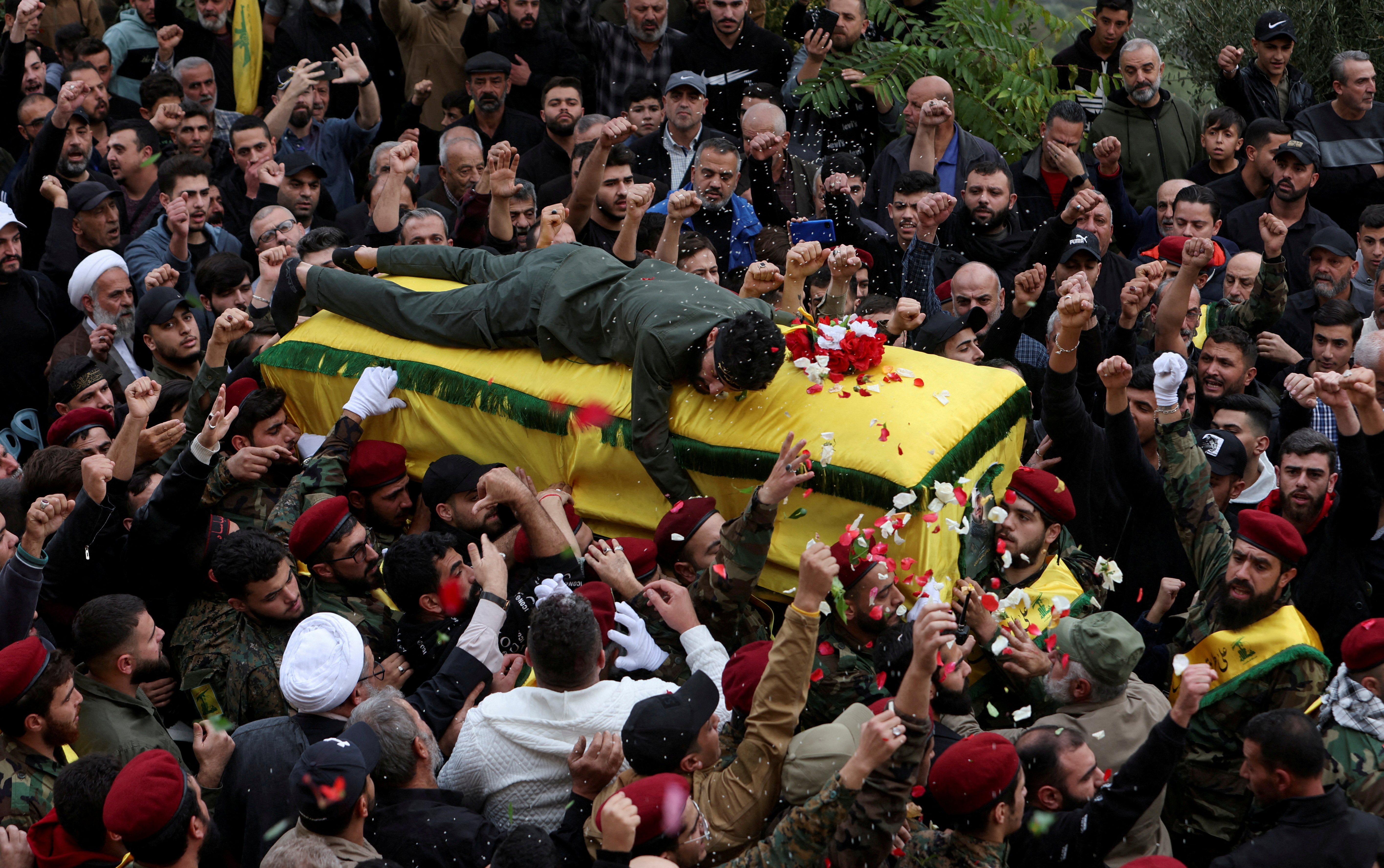 A member of Hezbollah mourns as he lies on top of the coffin of Hezbollah member Jaafar Serhan, during his funeral in Mashghara