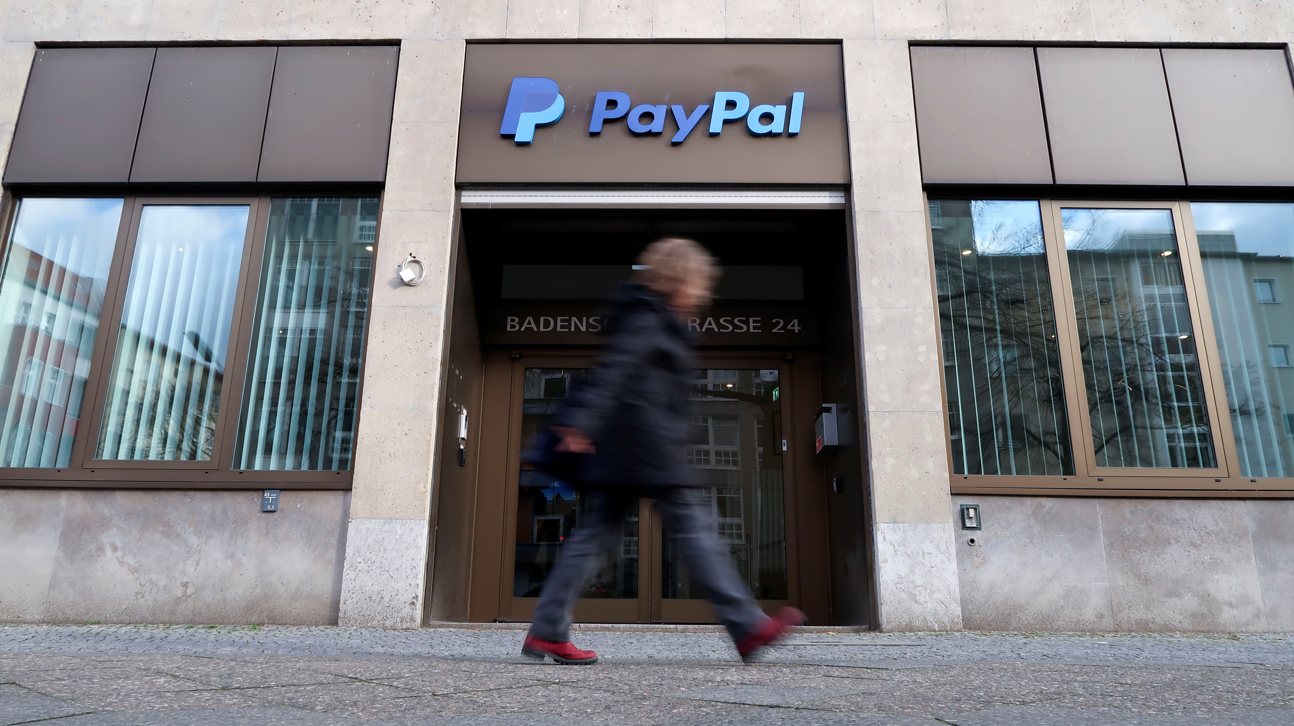 A pedestrian walks past the PayPal logo at an office building in Berlin