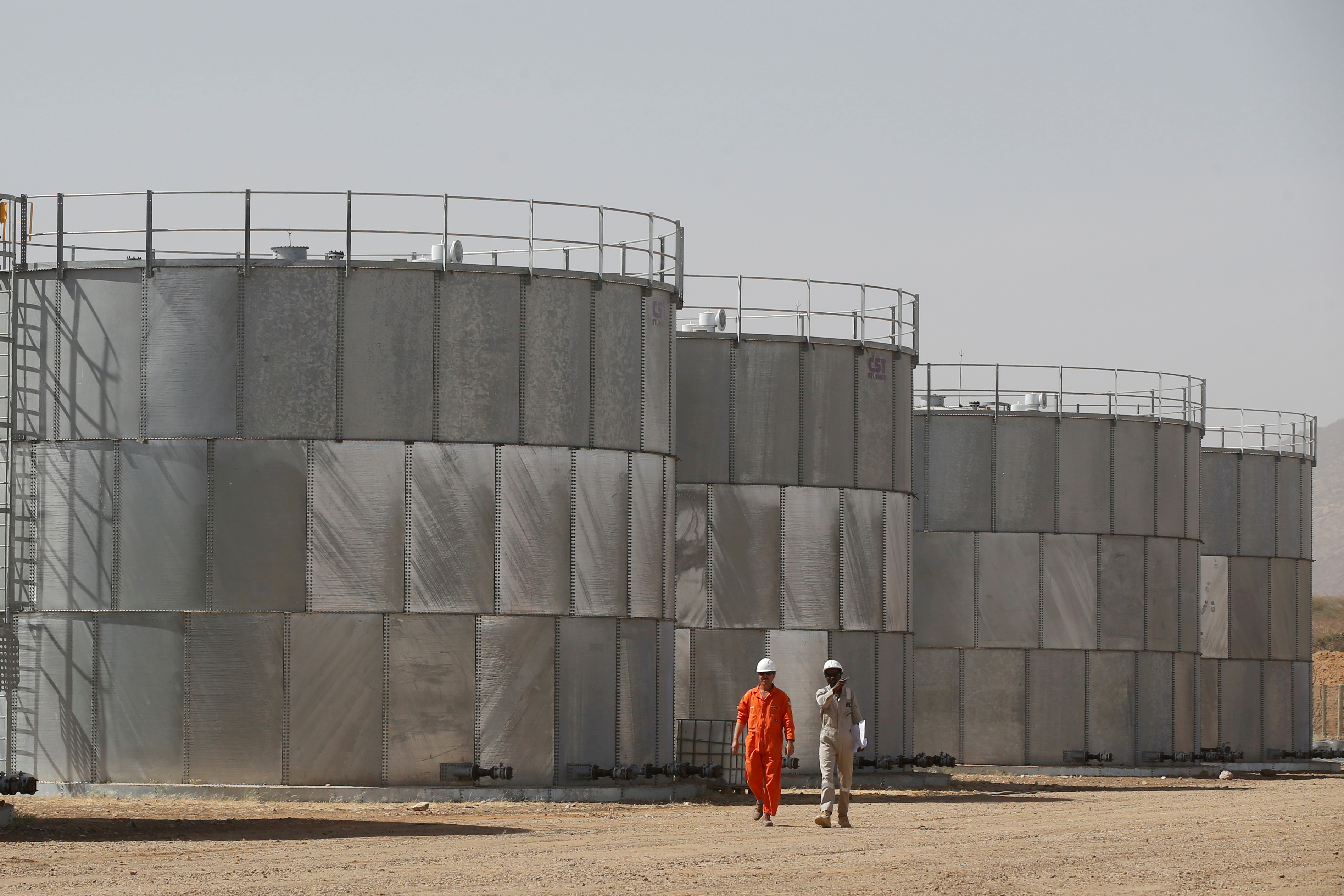 Workers walk past storage tanks at Tullow Oil's Ngamia 8 drilling site in Lokichar